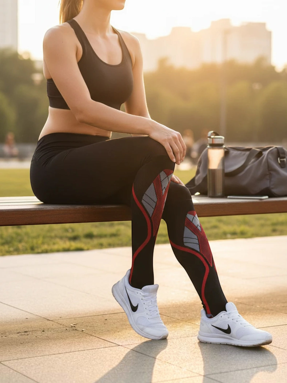 Kotyss knee high compression socks in black and red with athletic padding, worn by a woman sitting on a park bench.