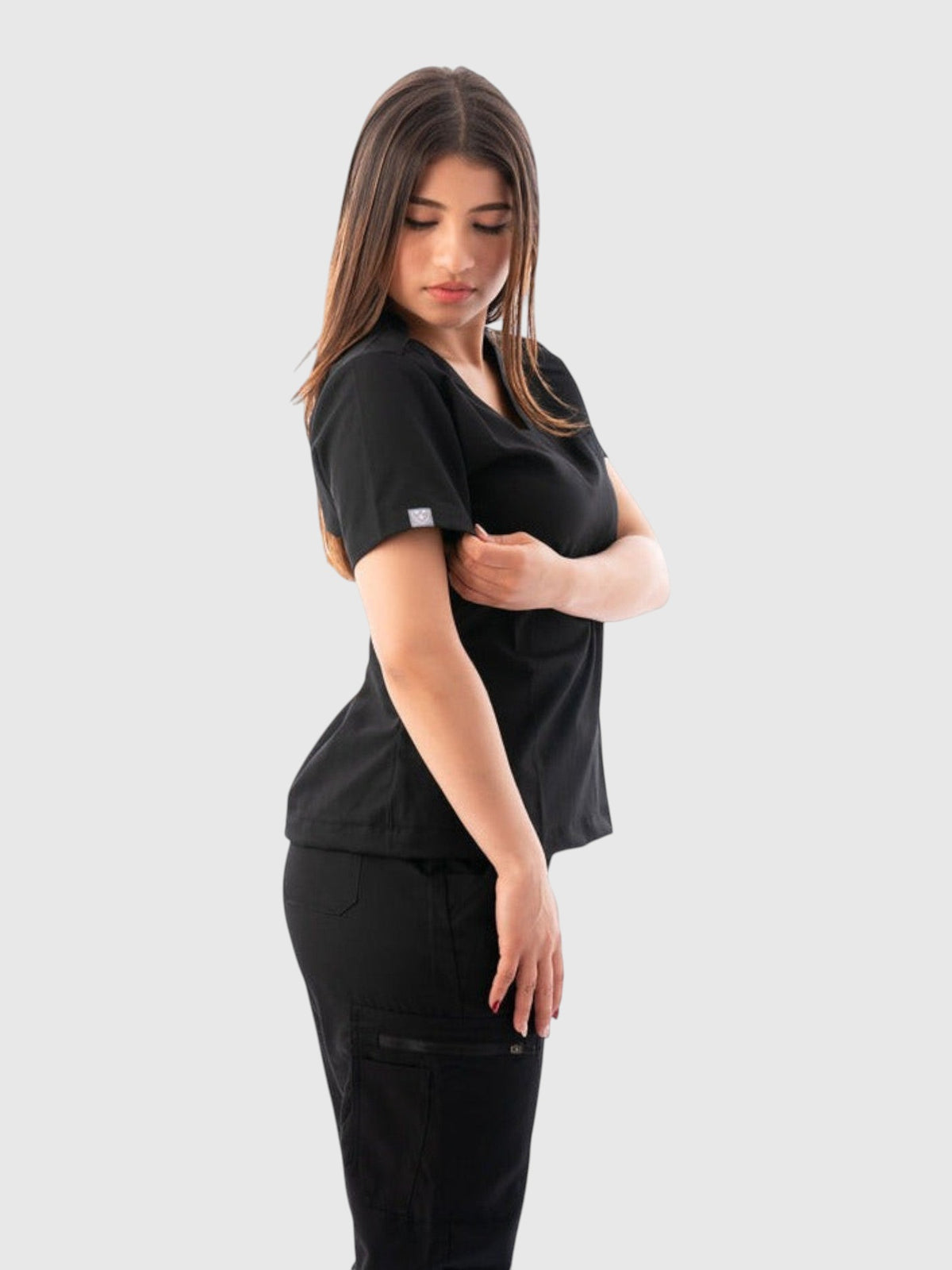 A model wearing a black Kotyss V-neck scrub top and matching jogger pants with multiple utility pockets.