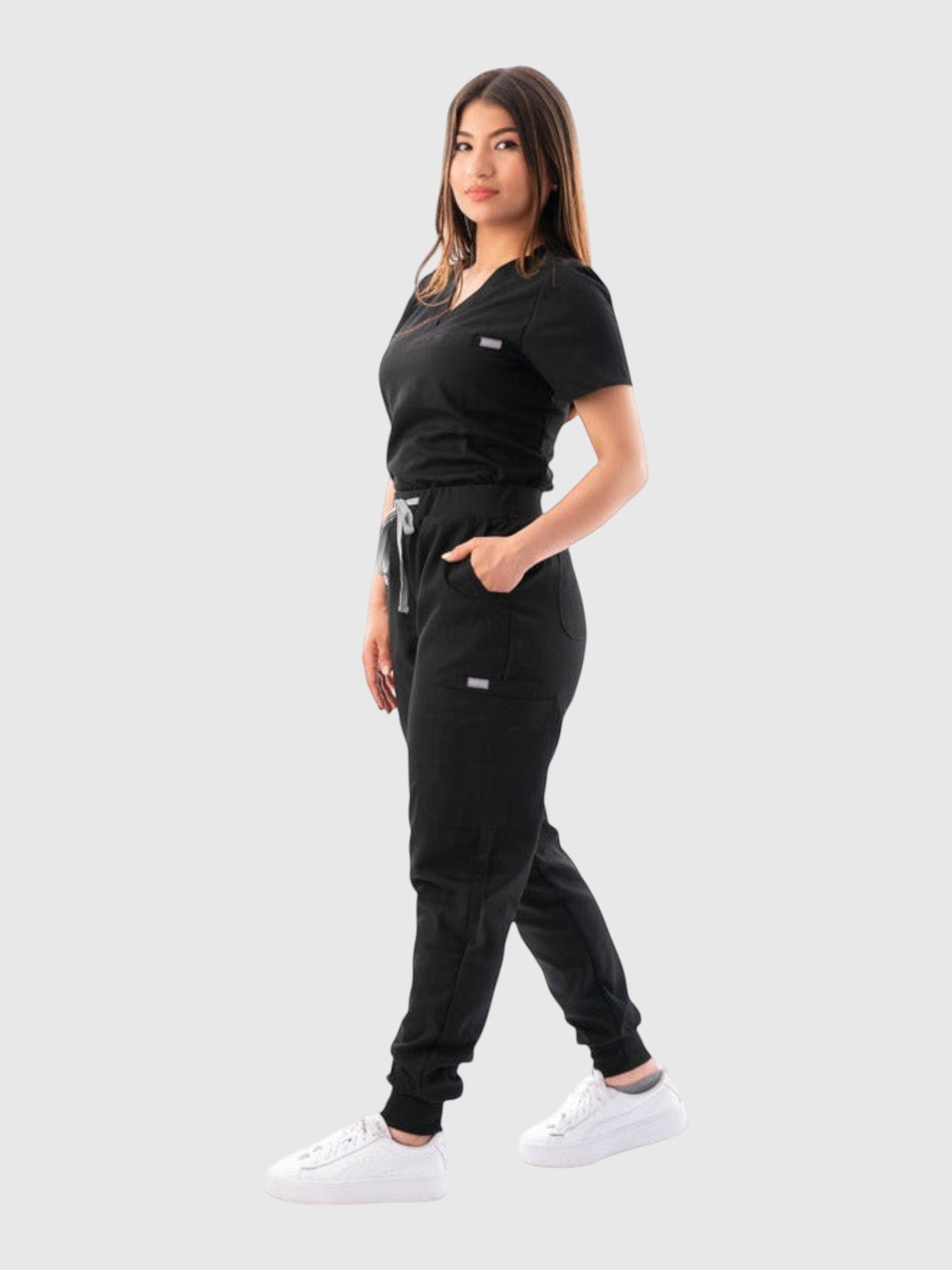 Kotyss women's black V-neck scrub top and jogger pants set with multiple pockets, worn by a model.