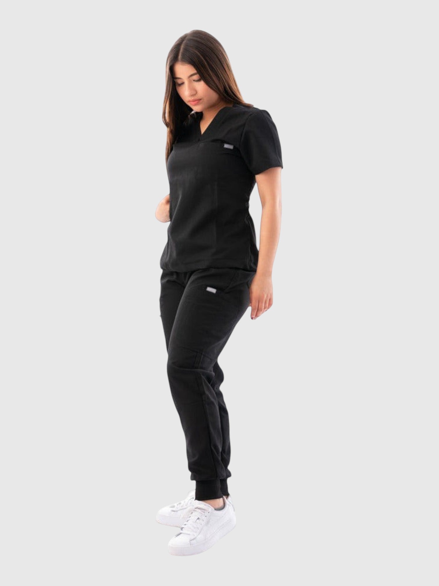 Kotyss women's black V-neck scrub top and jogger pants set with 4-way stretch fabric on a model.