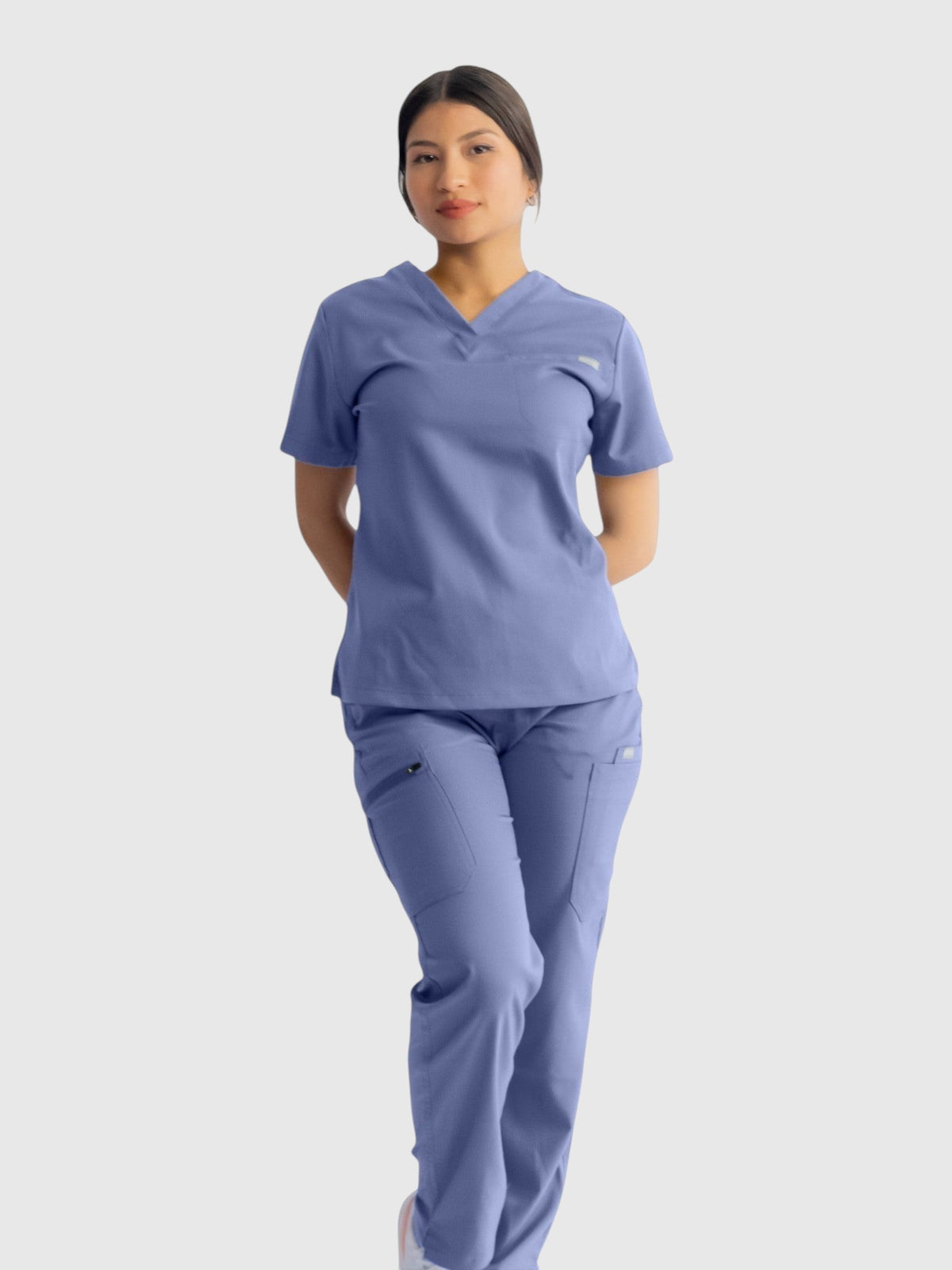 A woman wearing Kotyss blue straight cut medical scrub pants and matching v-neck top with multiple utility pockets.