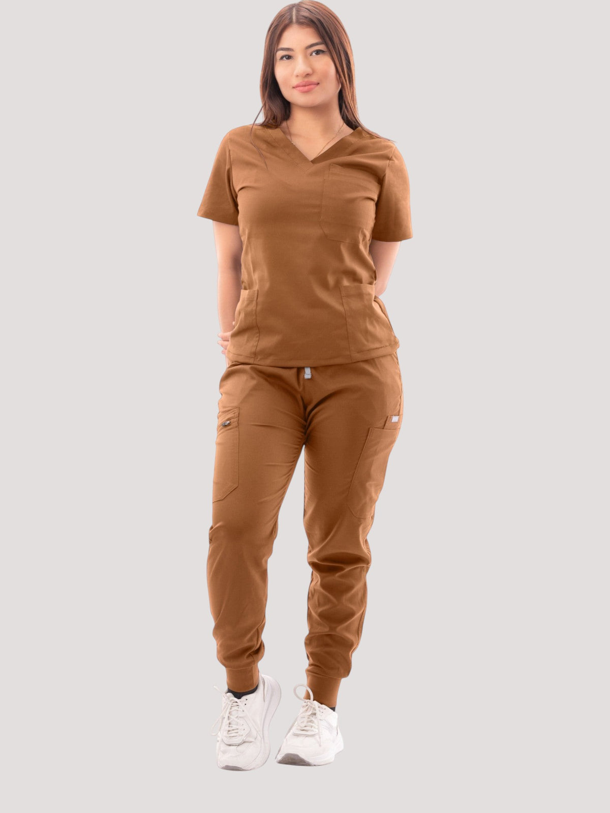 A model wearing a brown Kotyss V-neck scrub top and matching multi-pocket jogger pants on a white background.
