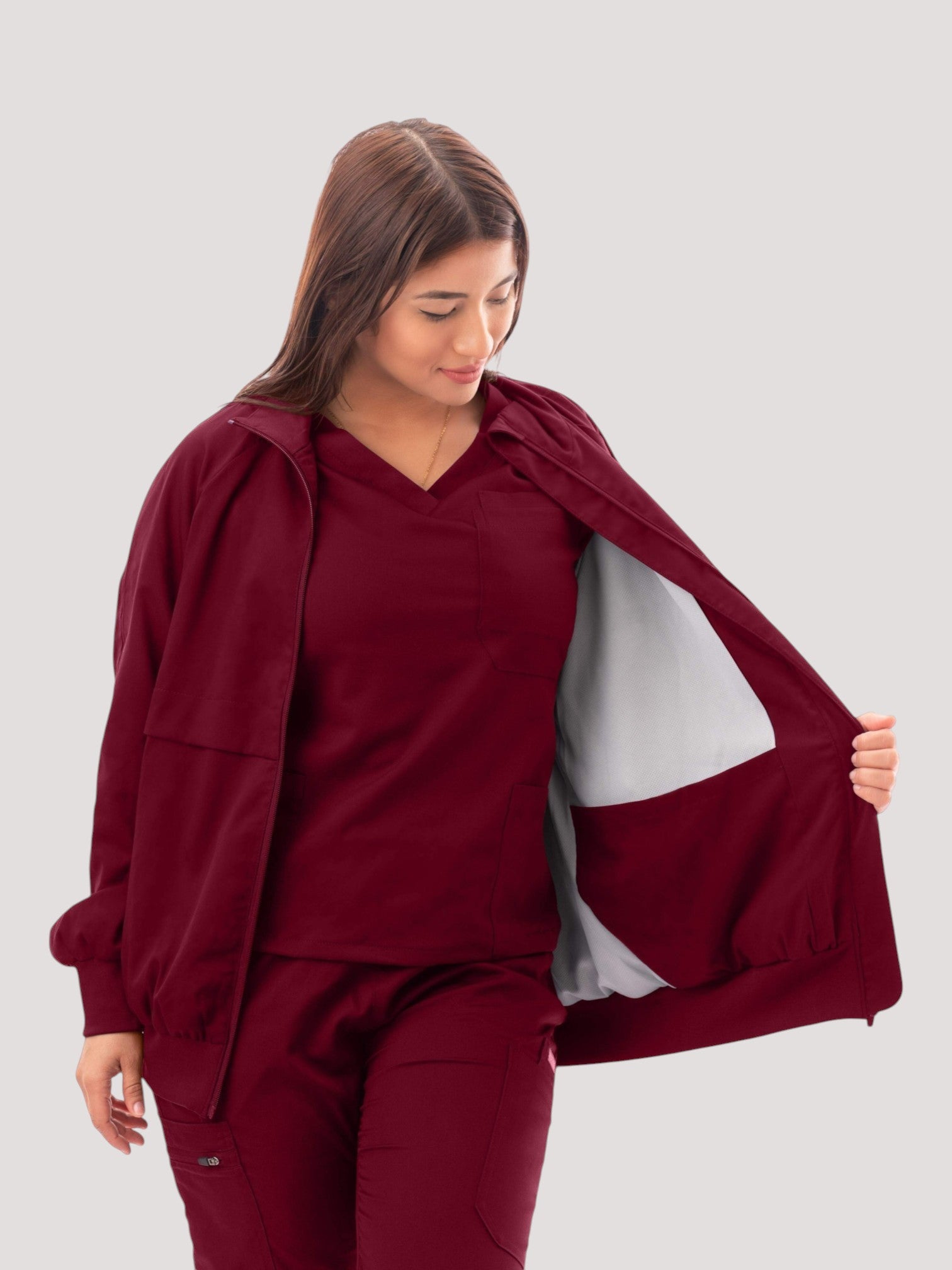 Kotyss women's burgundy scrub jacket featuring a high neck, ribbed cuffs, and a soft white interior lining.