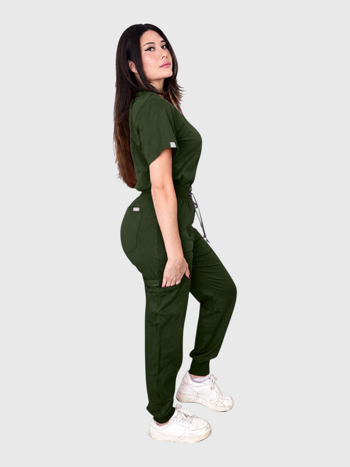 Model wearing a dark green Kotyss V-neck scrub top and multi-pocket jogger pants set with a side view