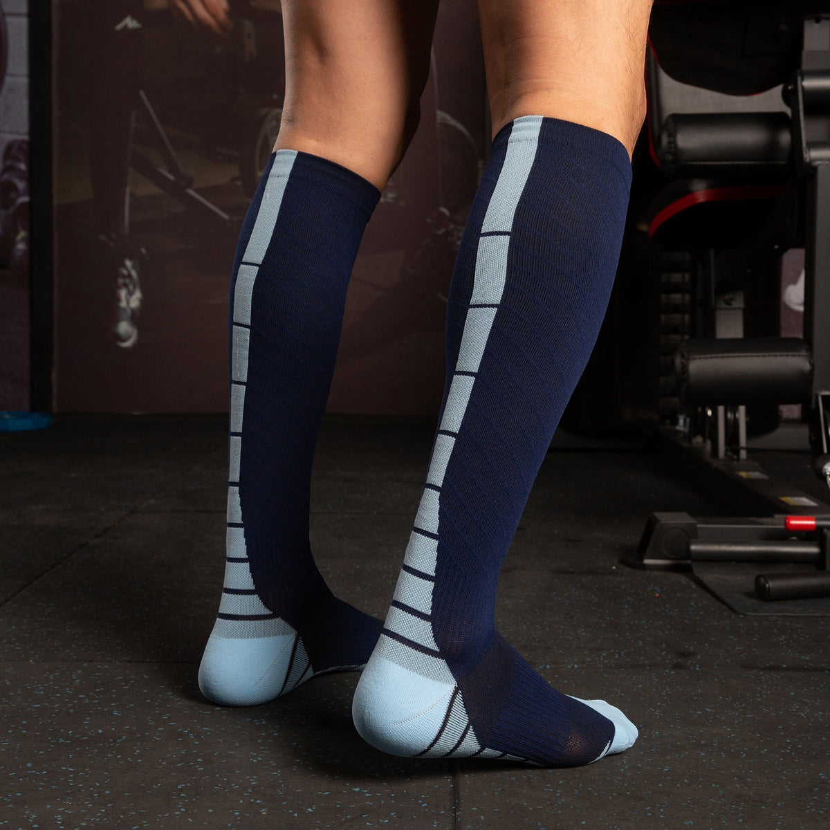 Kotyss navy blue and light blue knee-high athletic compression socks with seamless design on a person in a gym