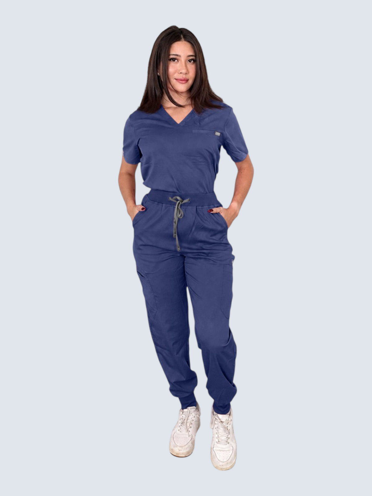 Model wearing a navy blue Kotyss V-neck scrub top and multi-pocket jogger pants set with a comfortable fit.