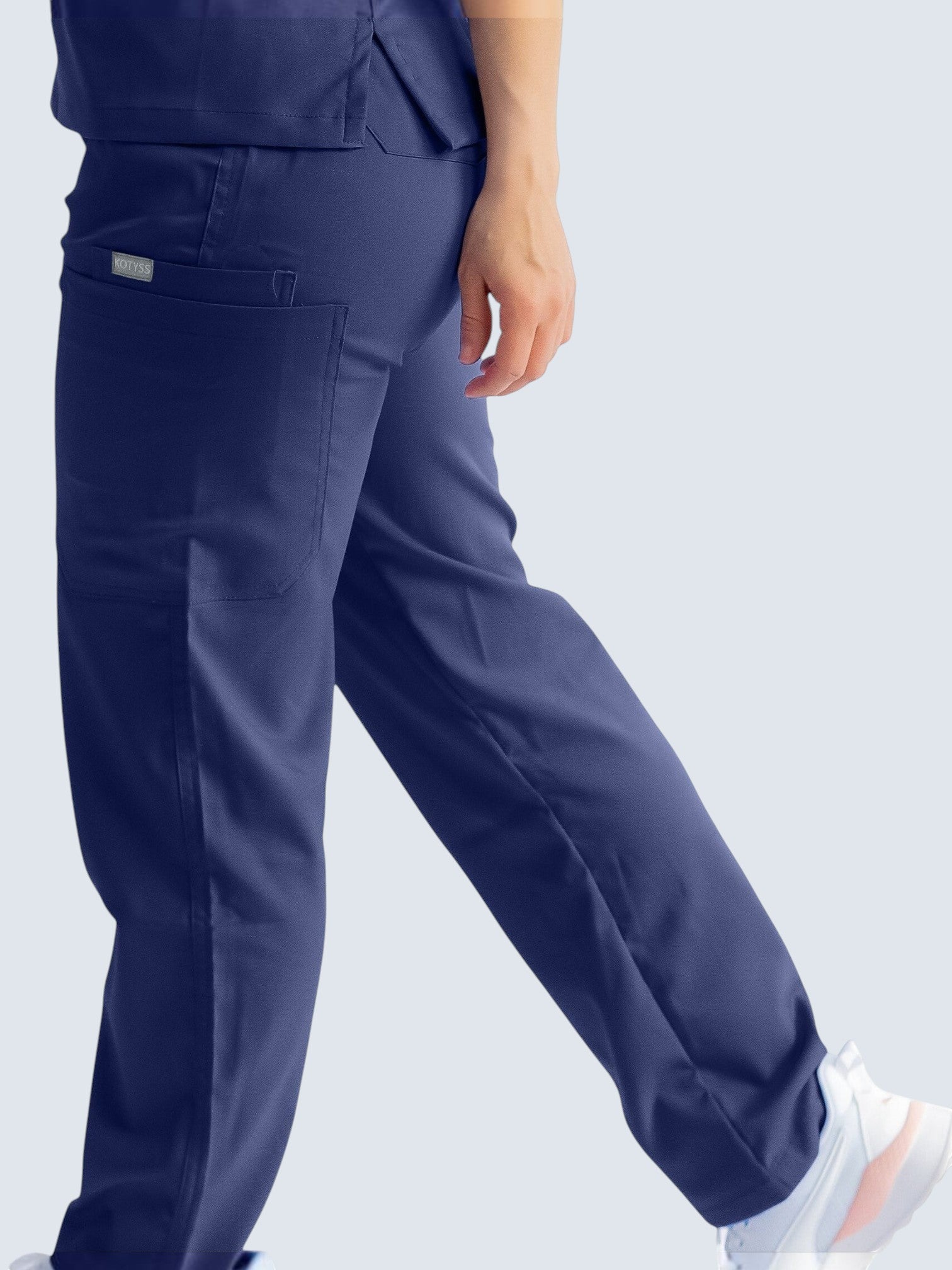 Kotyss navy blue straight cut medical scrub pants with multiple utility pockets, worn by a healthcare professional.