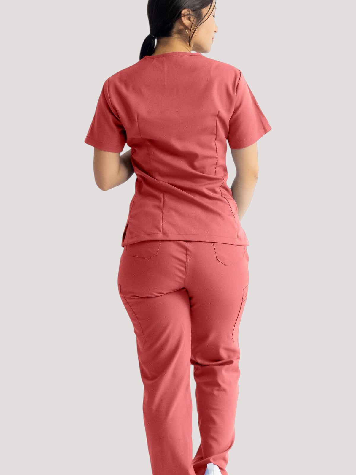 Kotyss straight cut medical scrub pants in coral pink, featuring a multi-pocket design and breathable 4-way stretch.