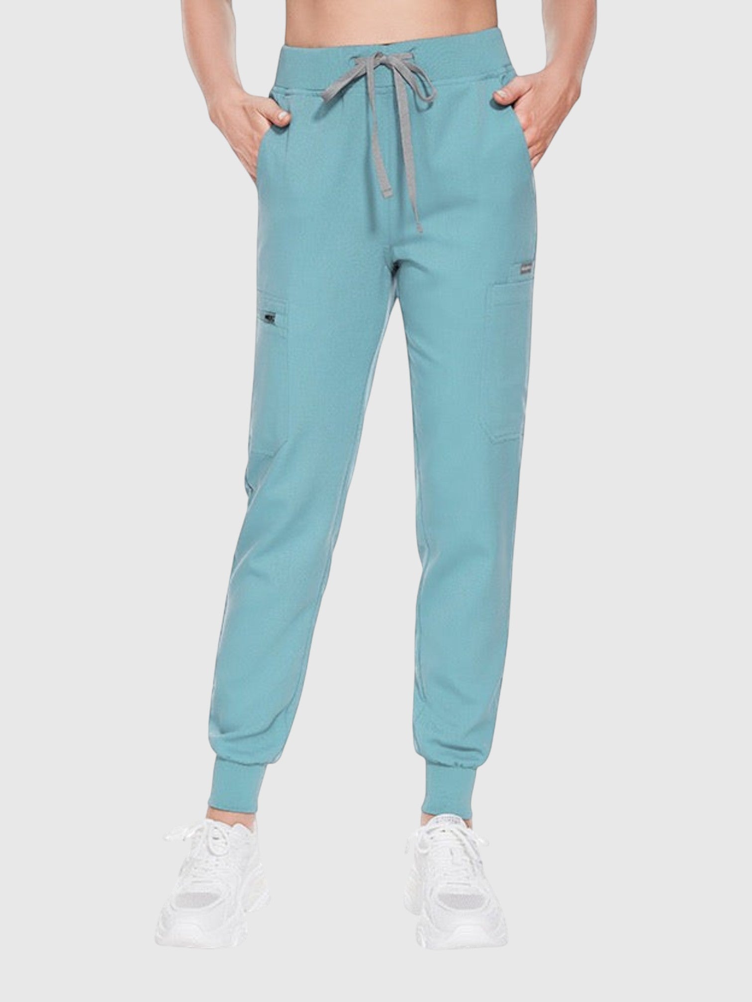 Kotyss teal blue medical scrub jogger pants with a drawstring waist and multiple utility pockets on a model