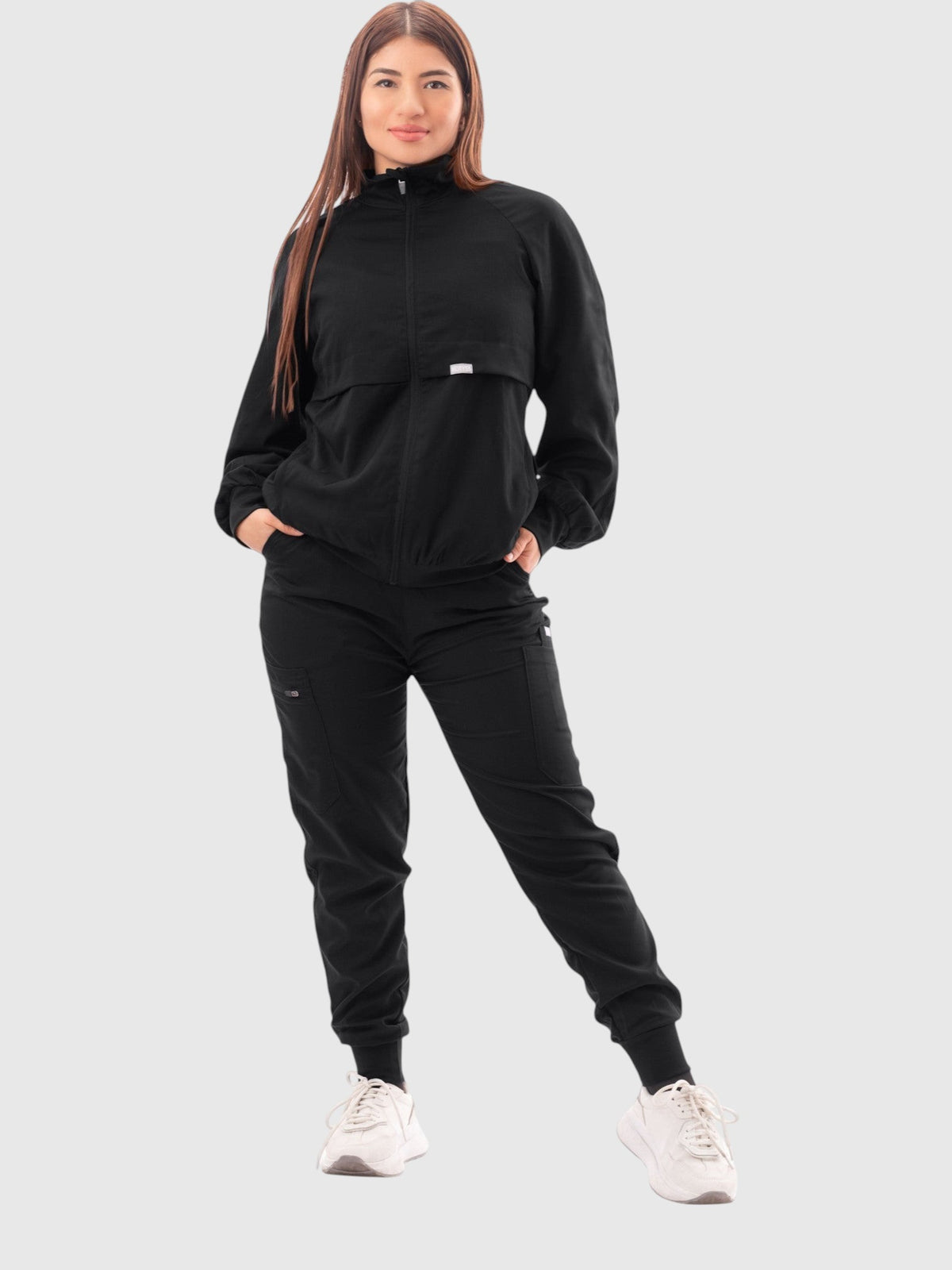 Kotyss women's black scrub jacket with high windbreaker neck, ribbed cuffs, and pockets worn by a female model