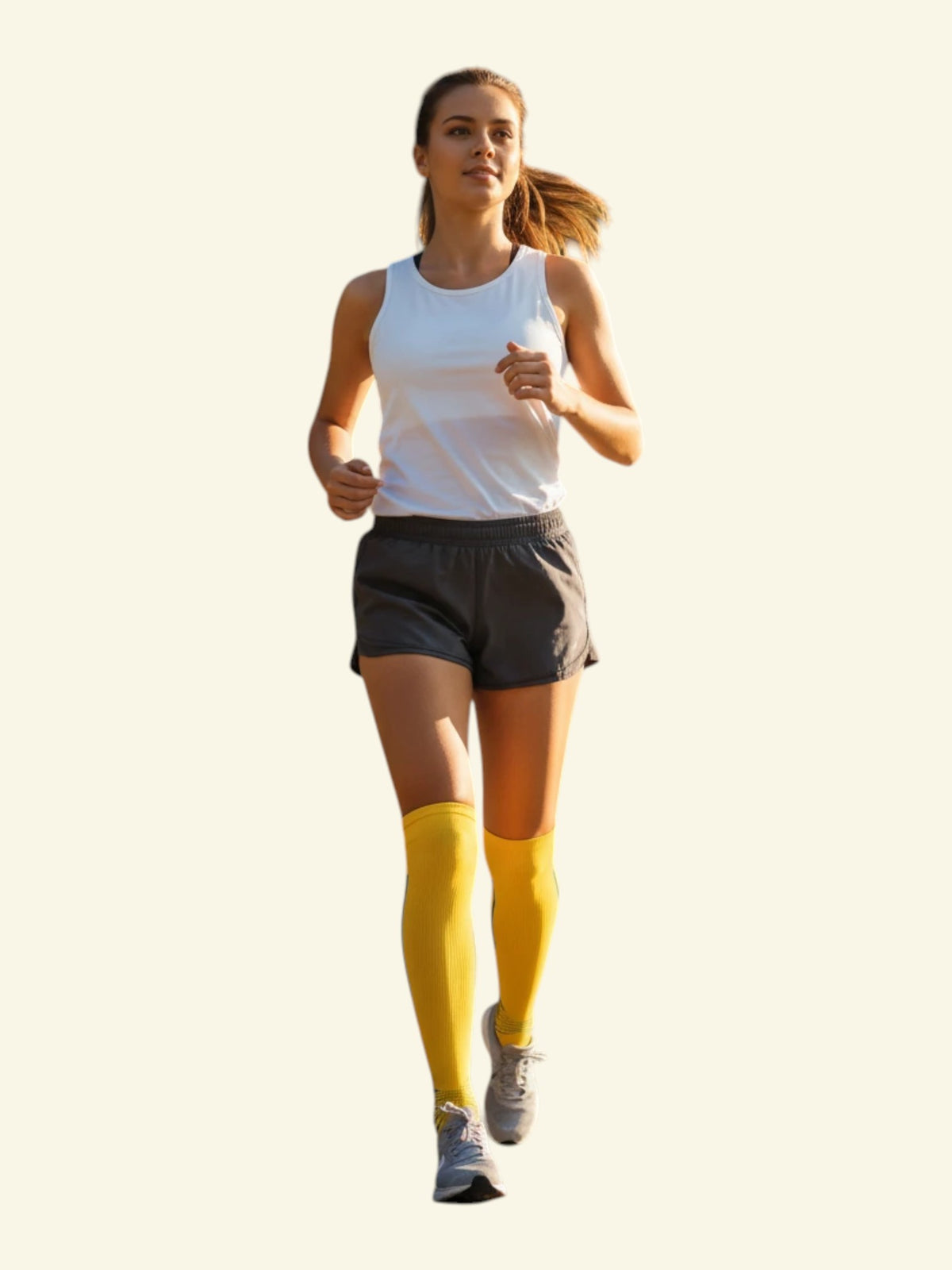 A woman running in Kotyss yellow knee-high compression socks, white tank top, and grey shorts for athletic support.
