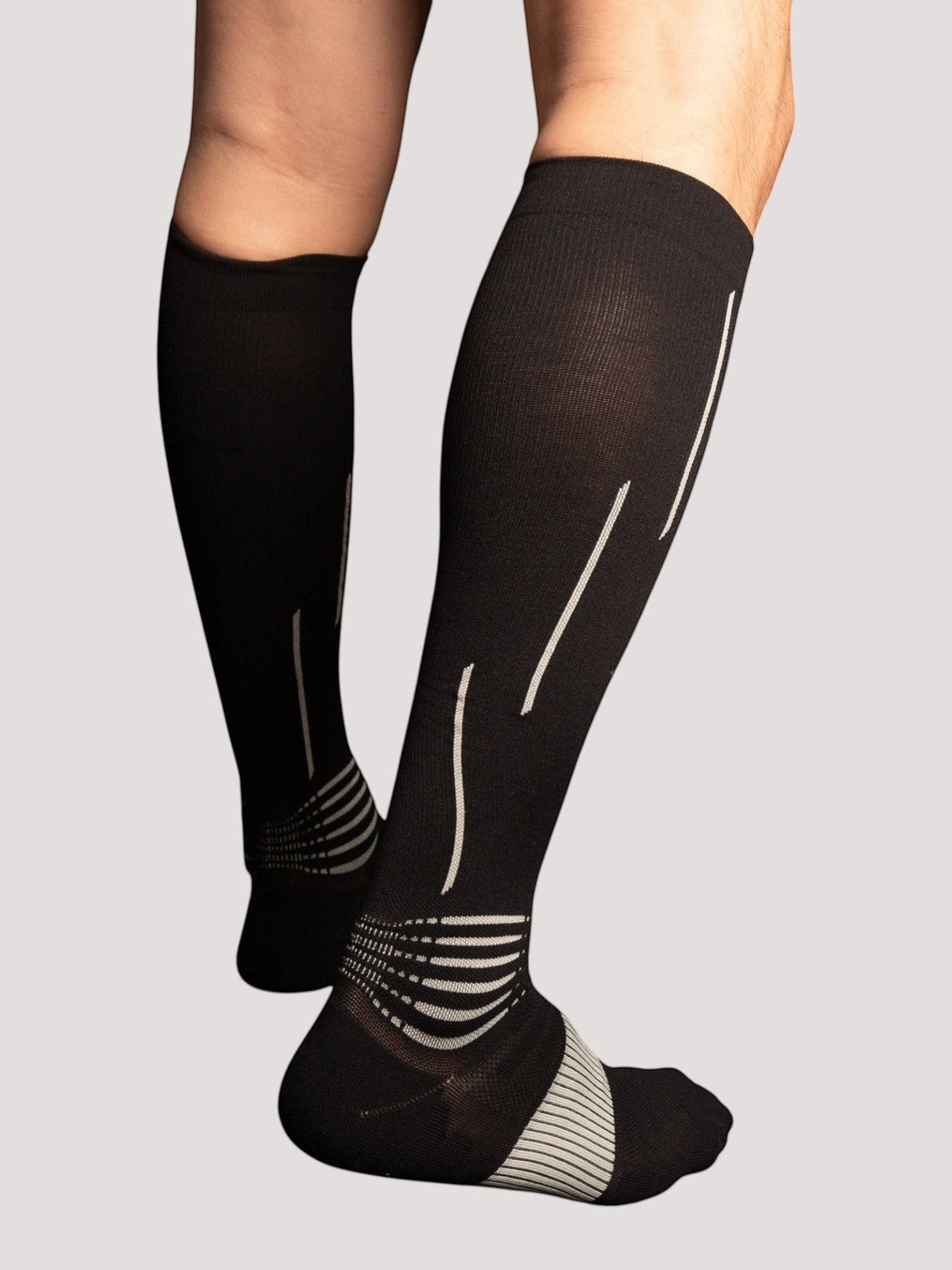 Kotyss black athletic compression knee high socks with white accent lines on the calf and heel for support.