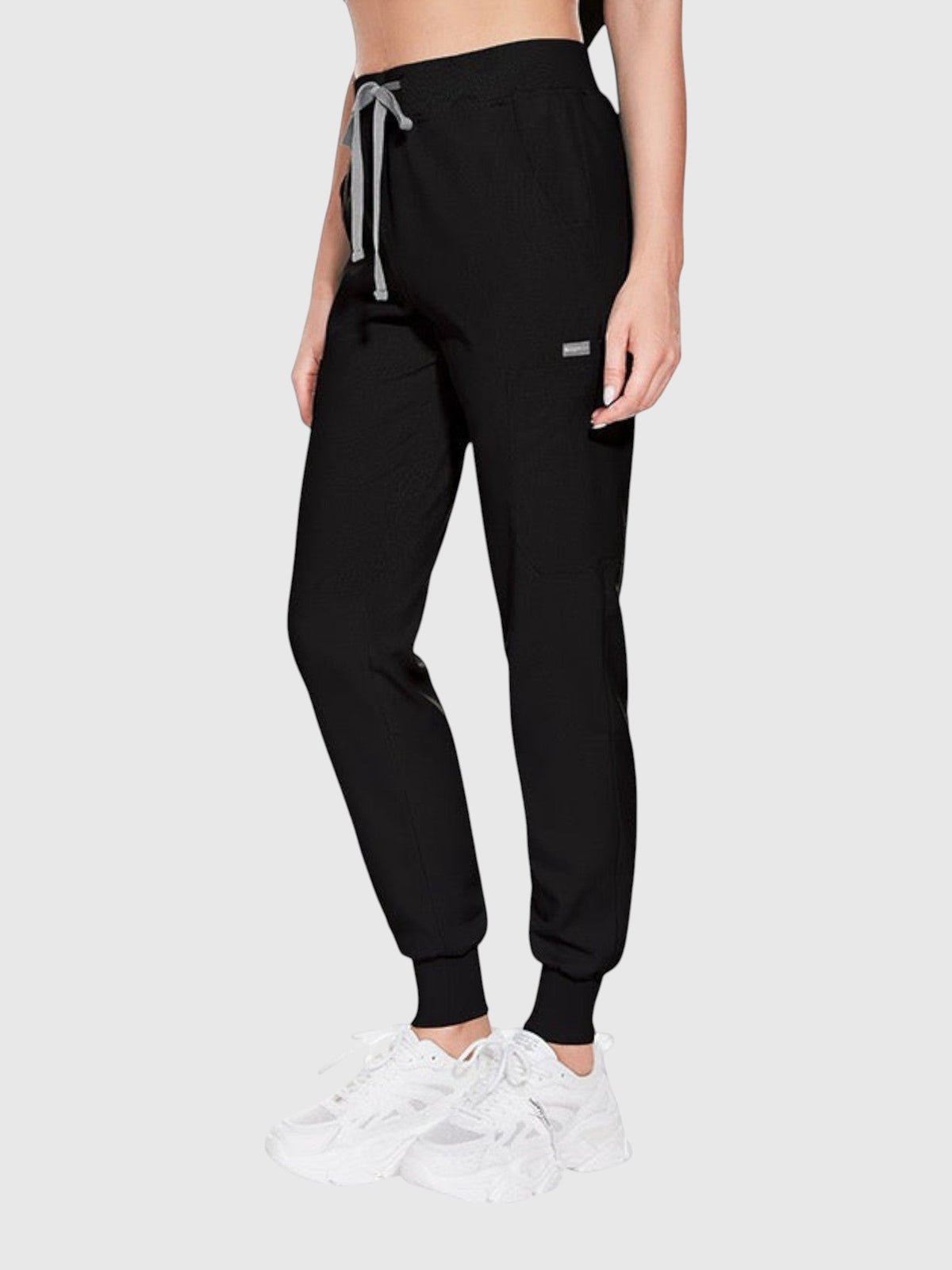 Model wearing Kotyss black medical scrub jogger pants with a drawstring waist and multiple utility pockets
