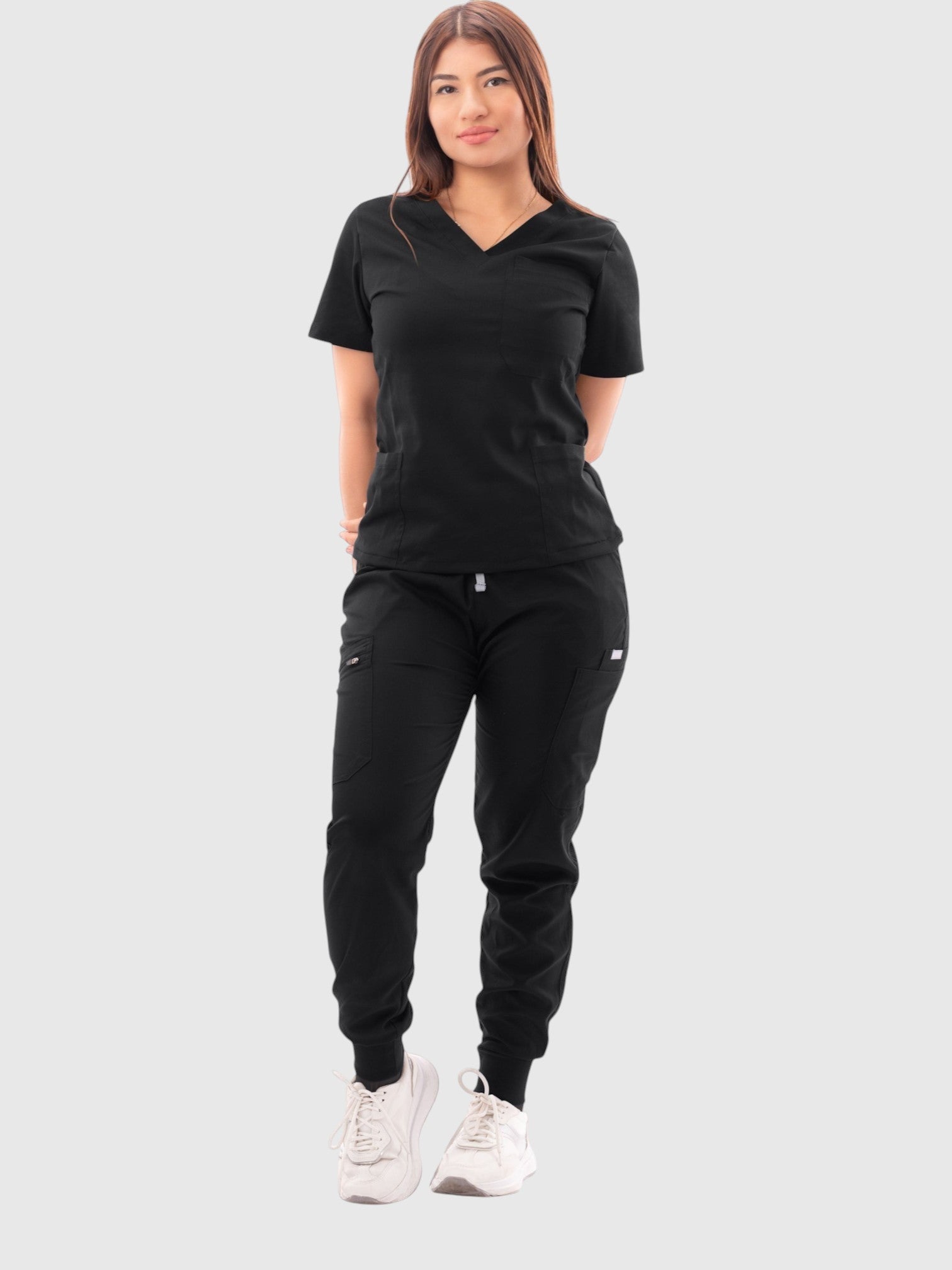Woman wearing a black Kotyss V-neck scrub top and multi-pocket jogger pants set with 4-way stretch fabric.
