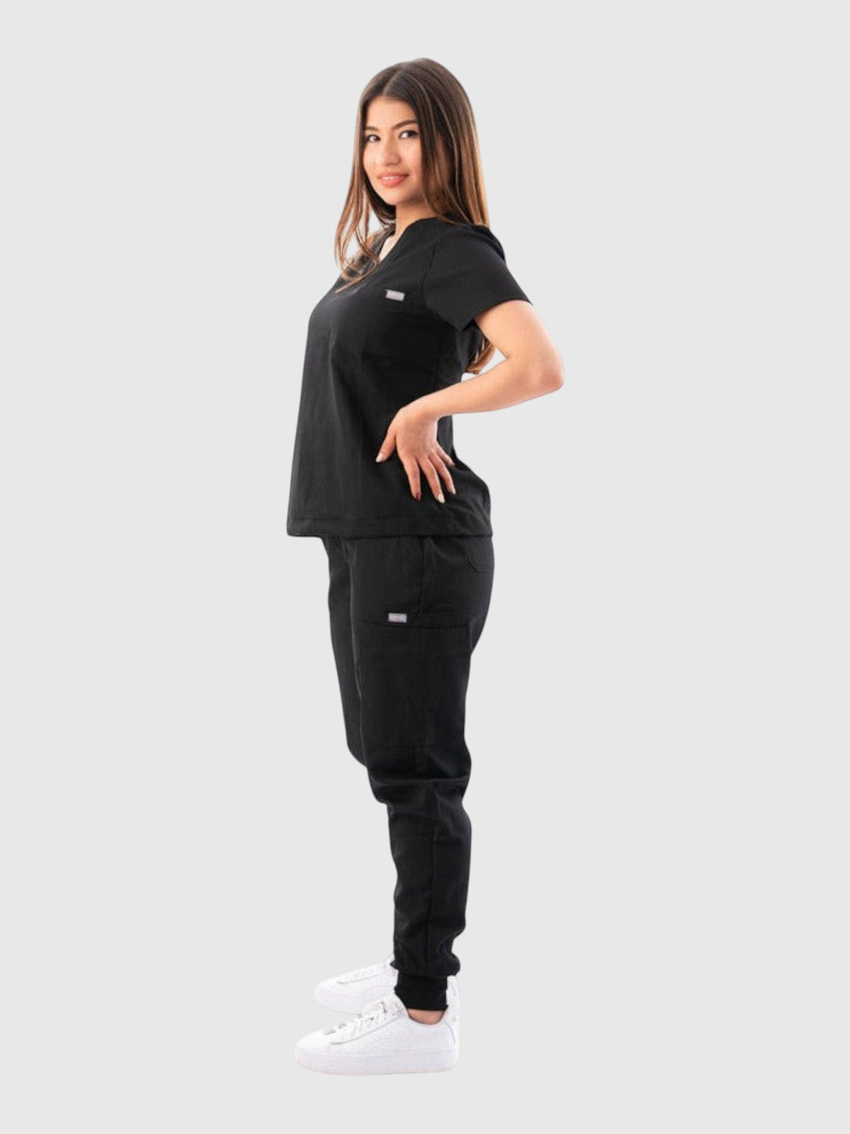 Kotyss black V-neck scrub top and jogger pants set worn by a woman in a side profile view.