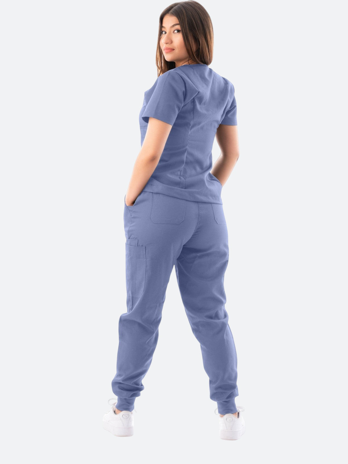 A woman wearing a Kotyss blue V-neck scrub top and jogger pants set, viewed from the back.