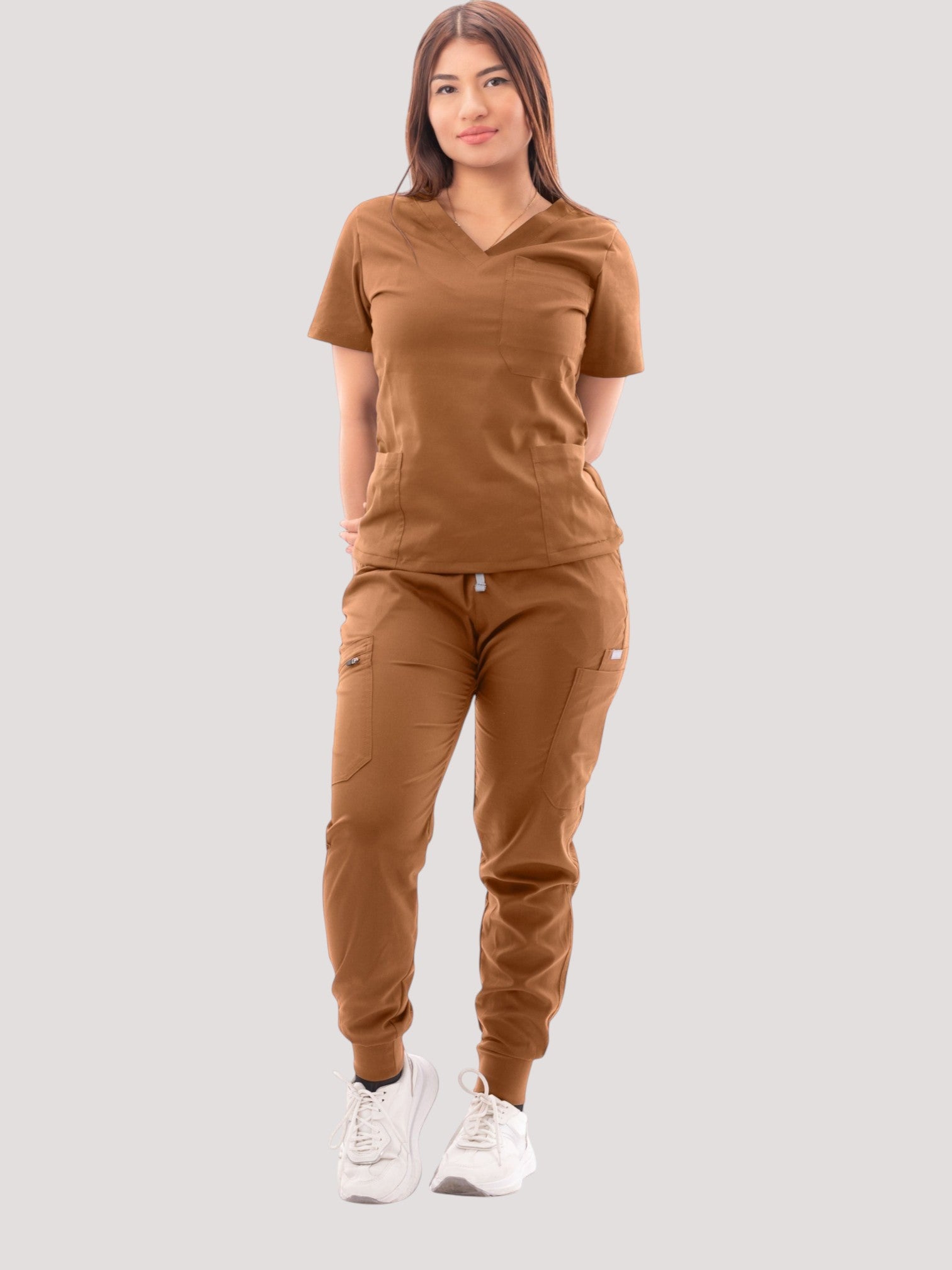 A model wearing a brown Kotyss V-neck scrub top and matching multi-pocket jogger pants on a white background.