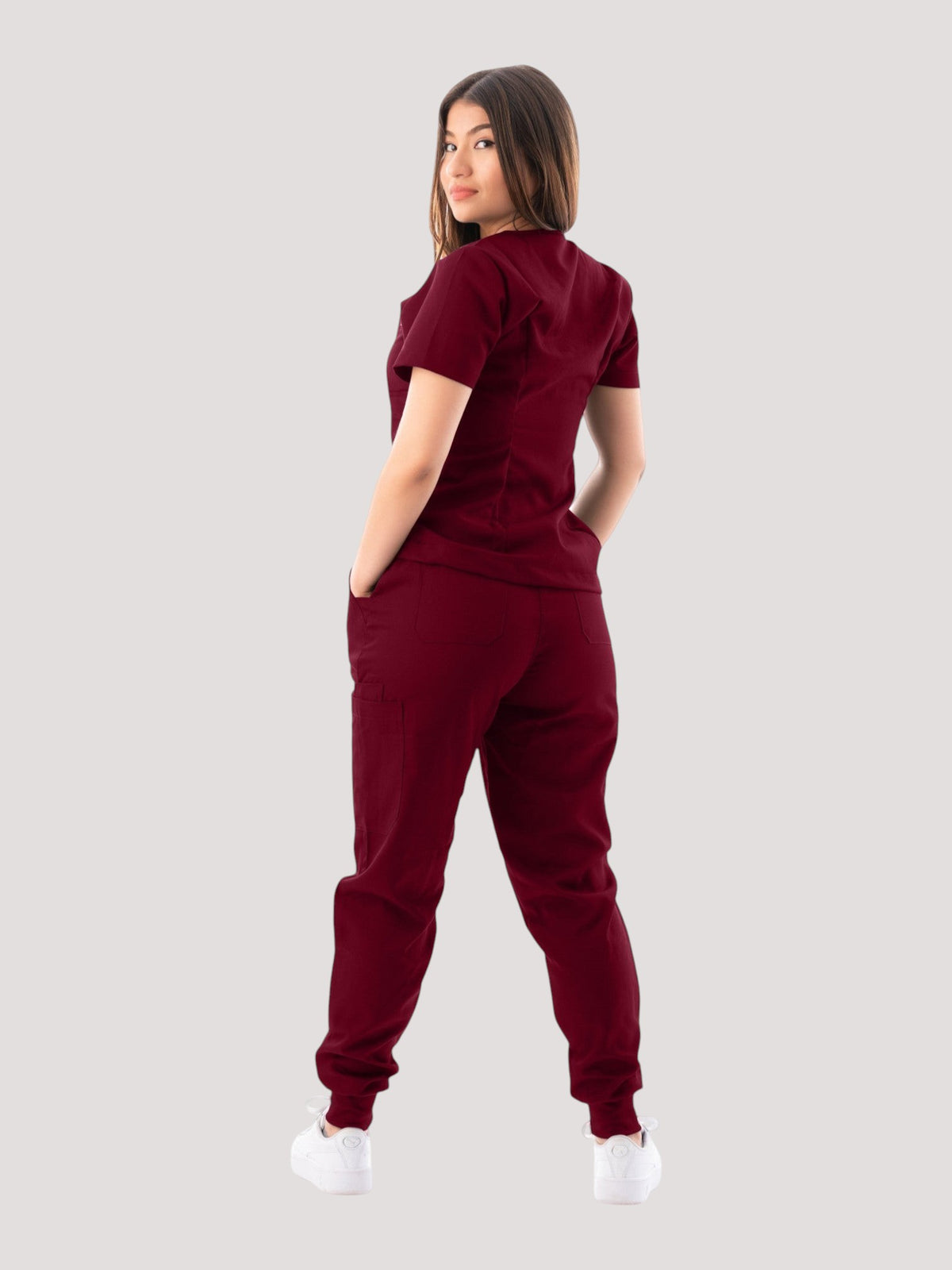 Model wearing a burgundy Kotyss V-neck scrub top and jogger pants set, back view, showing a professional fit.