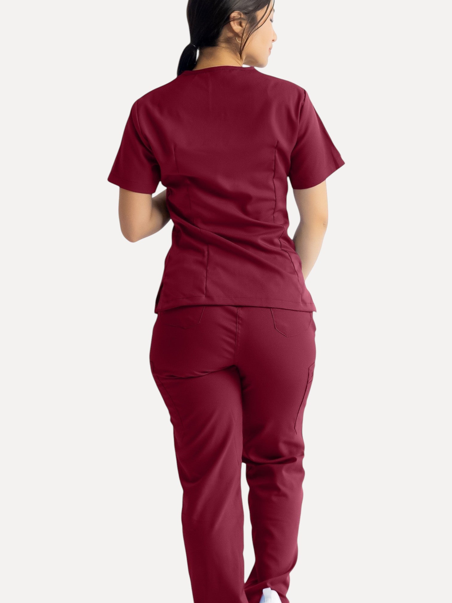 A woman wearing Kotyss burgundy straight cut medical scrub pants and matching top, viewed from the back.