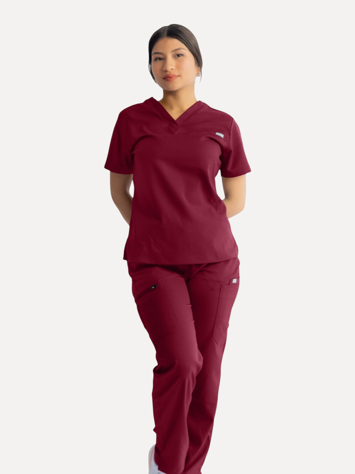 A woman wearing a Kotyss burgundy straight cut scrub set with multiple pockets, made from breathable stretch fabric.