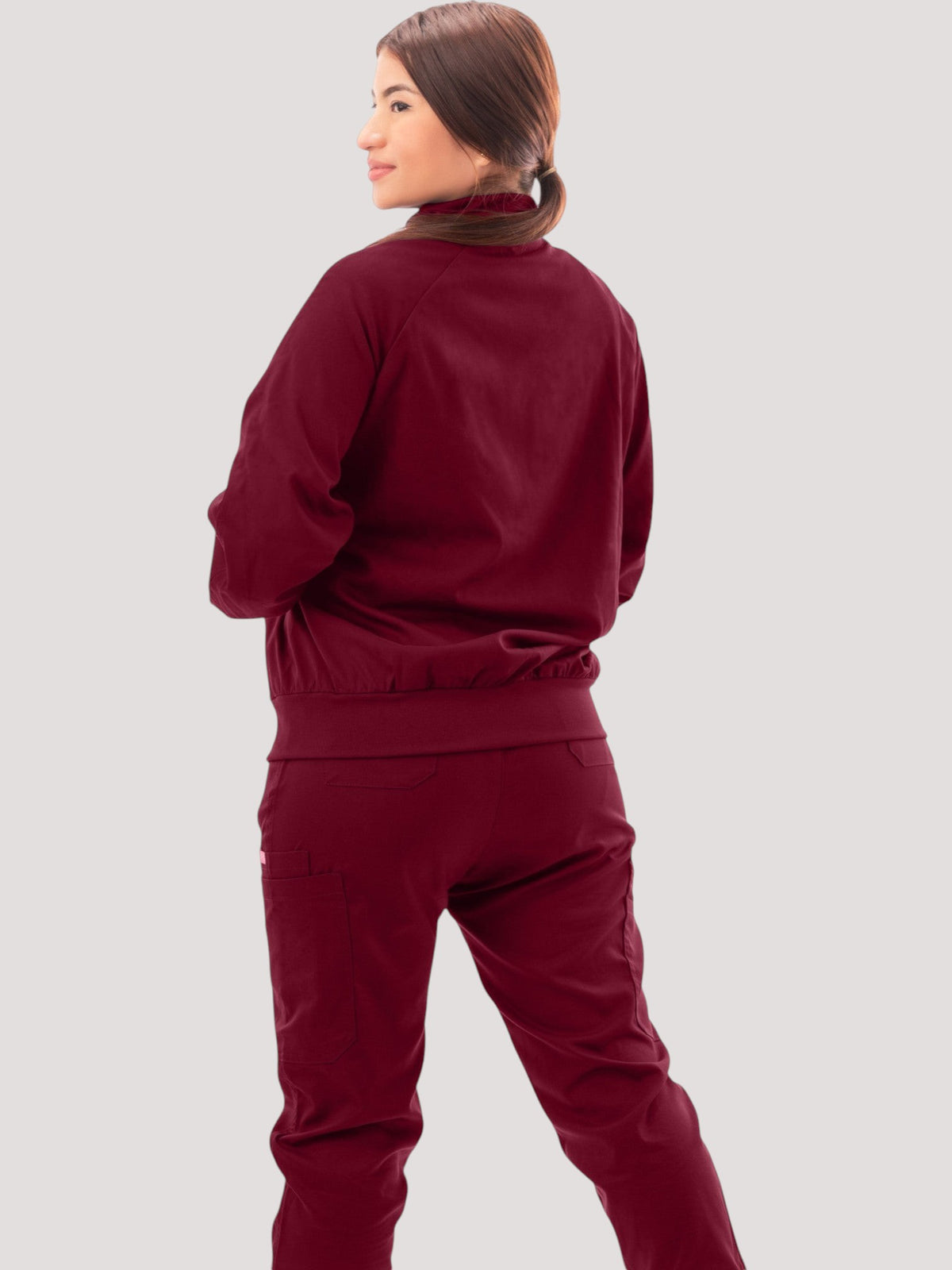 Kotyss women's burgundy scrub jacket with high neck and ribbed cuffs worn by a model, back view