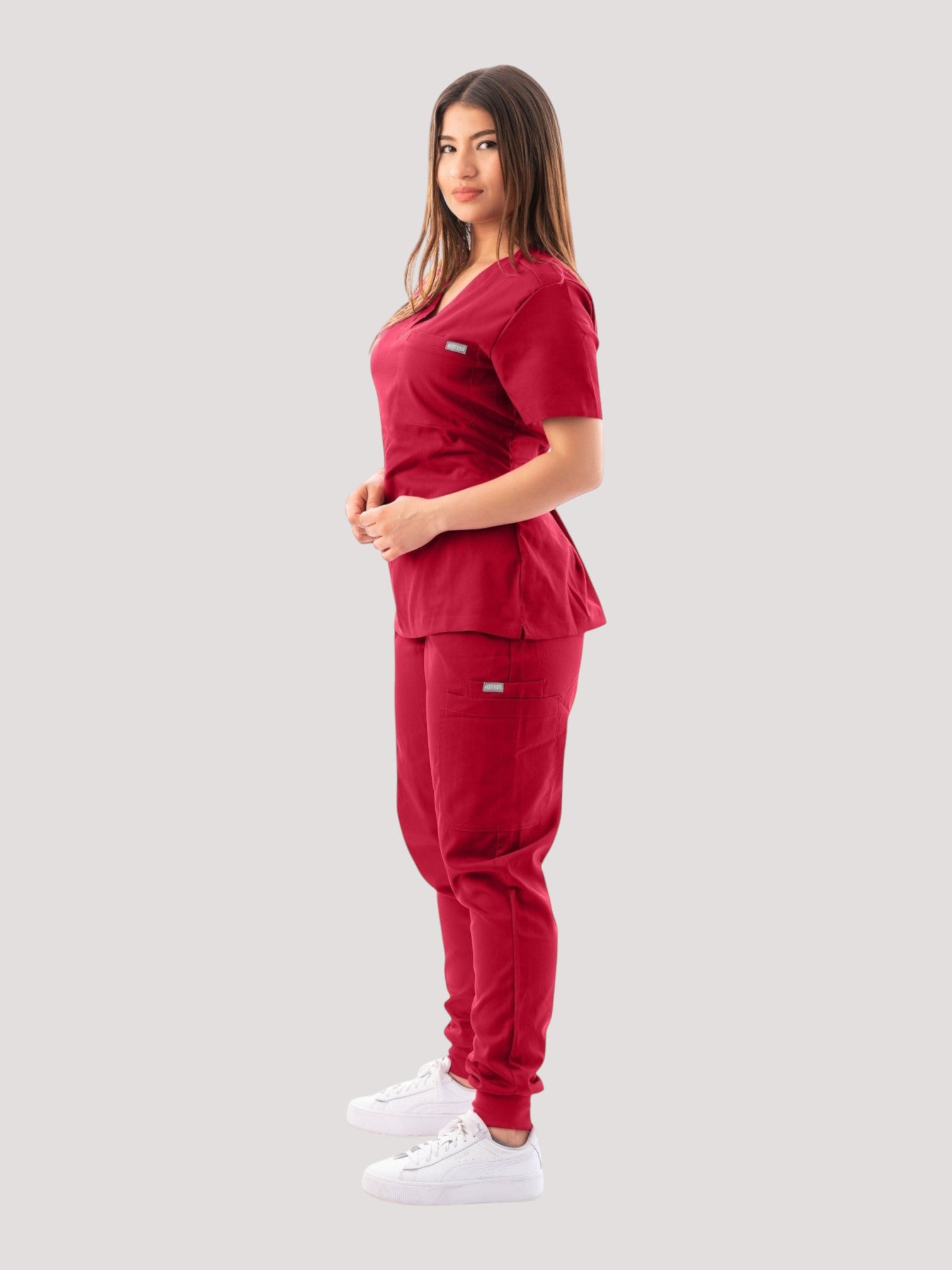 Kotyss women's burgundy V-neck scrub top and jogger pants set with multiple pockets, worn by a model.