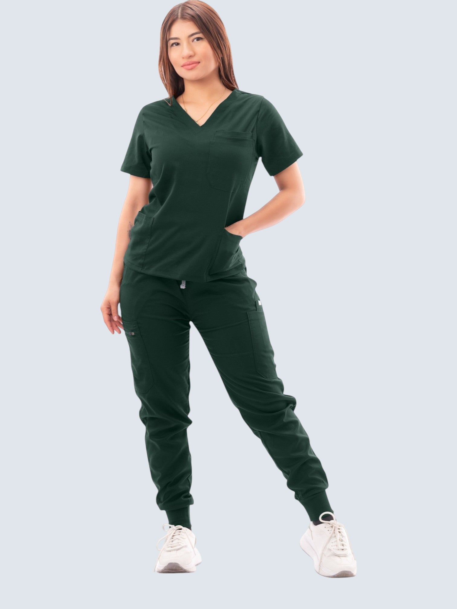 Kotyss dark green V-neck scrub top and jogger pants set with multiple pockets worn by a woman.