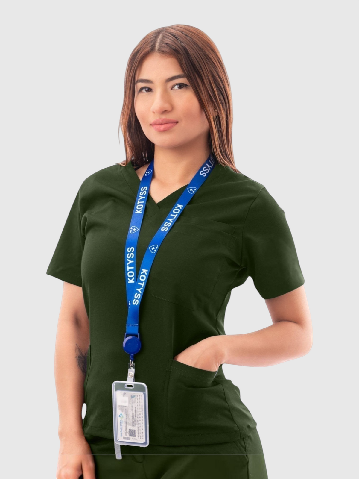 Woman wearing a dark green Kotyss V-neck medical scrub top with pockets and a branded blue lanyard