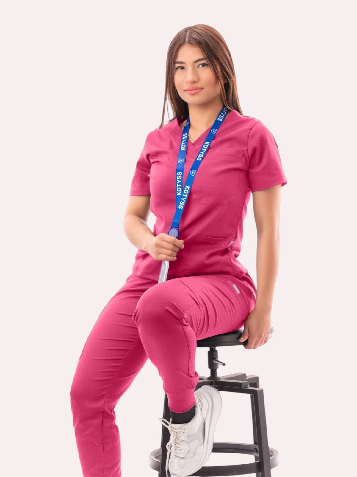 Kotyss women's fuchsia pink V-neck scrub top and jogger pants set with multiple pockets worn by a seated model