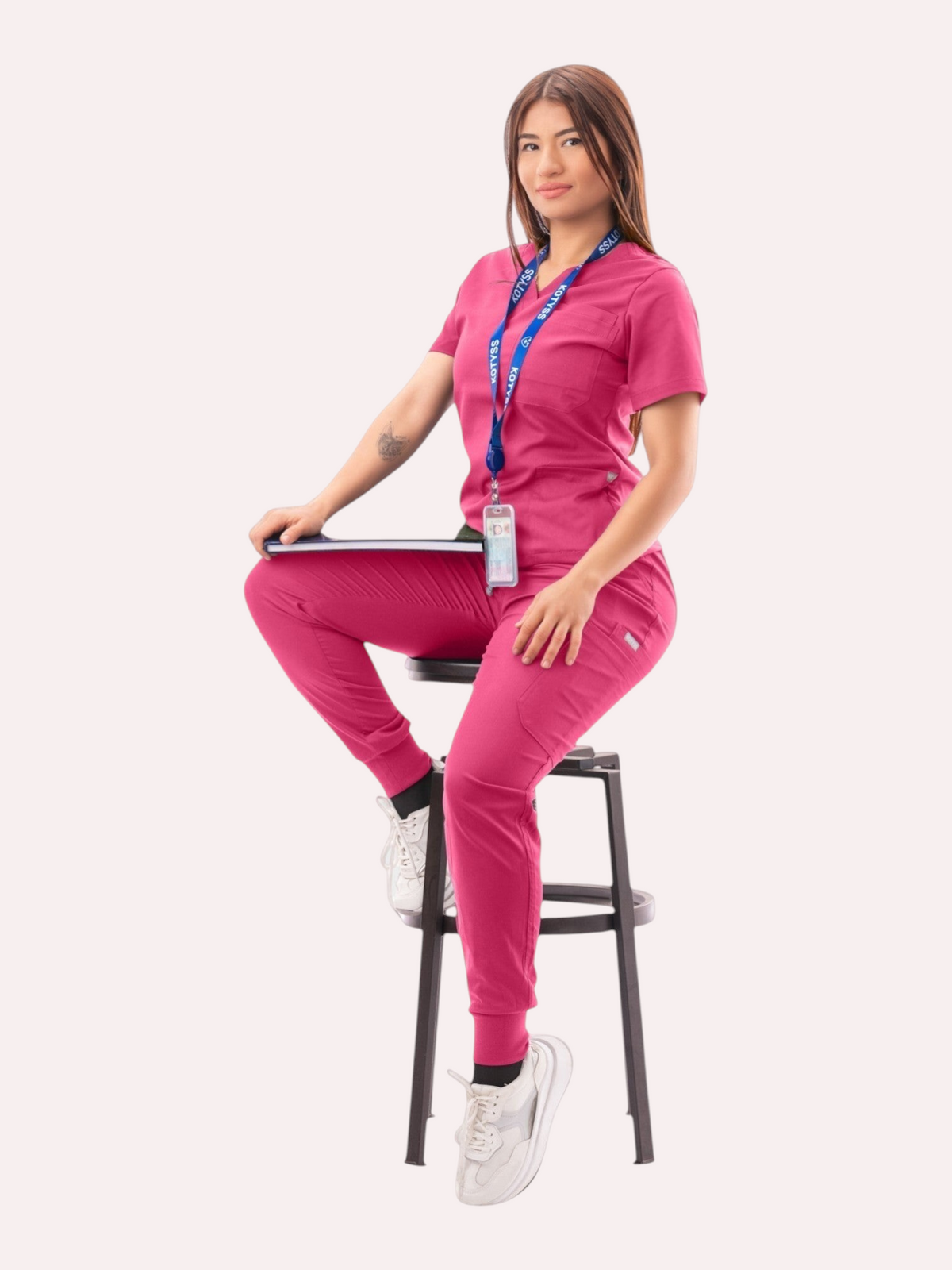 Kotyss women's fuchsia pink V-neck scrub top and jogger pants set with multiple pockets worn by a seated model