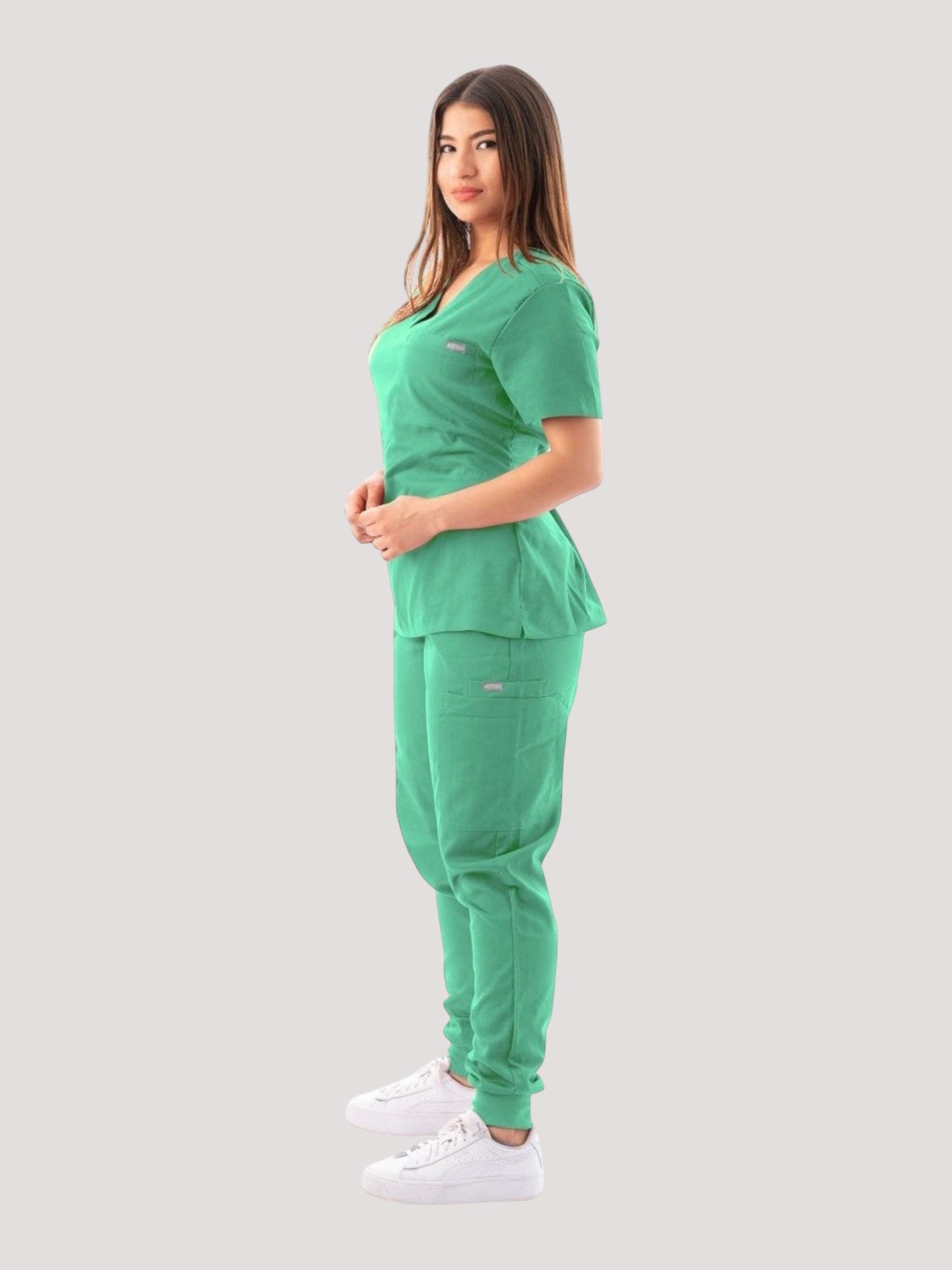 Kotyss green V-neck scrub top and jogger pants set worn by a woman, featuring breathable 4-way stretch fabric.