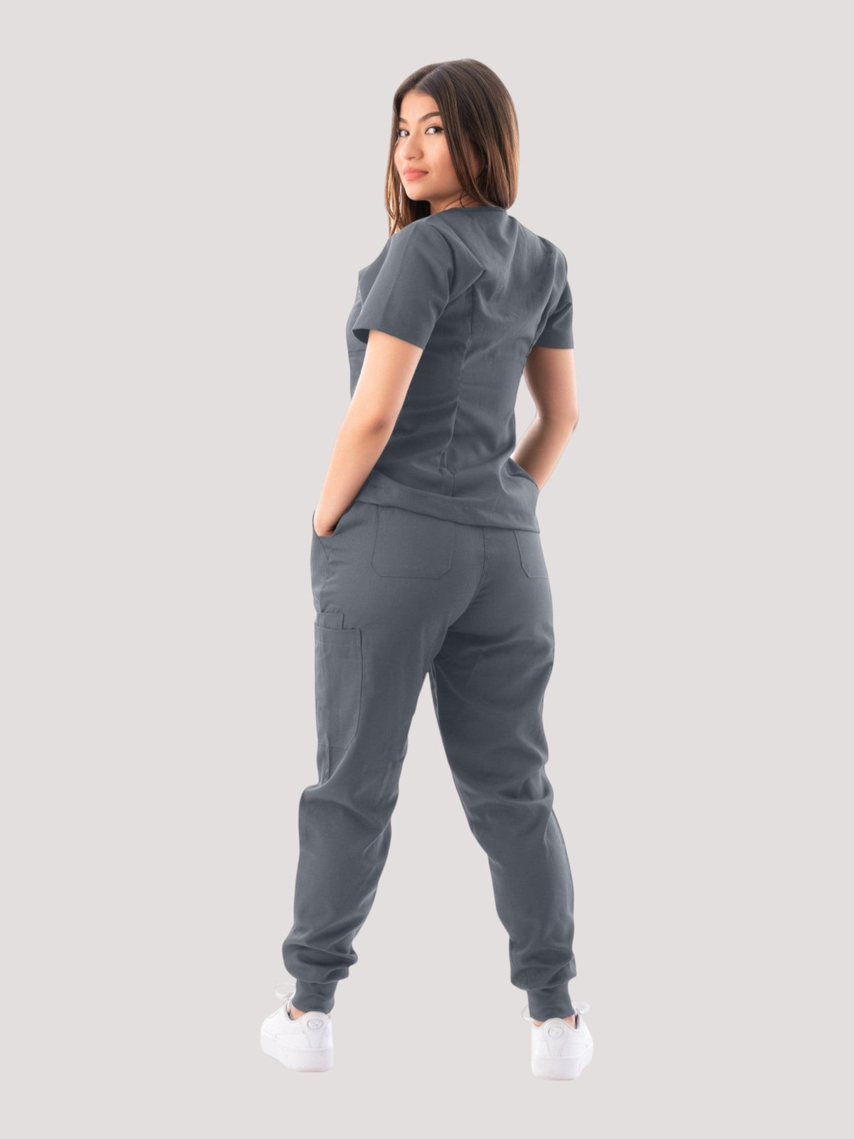 Kotyss women's grey V-neck scrub top and jogger pants set worn by a model, back view showing multiple pockets.