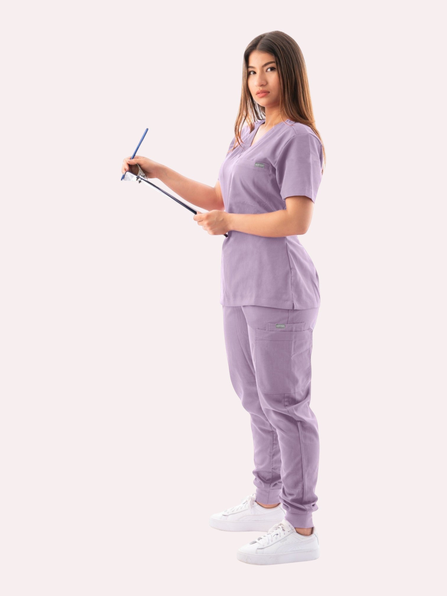 Kotyss women's lavender V-neck scrub top and jogger pants set with multiple pockets on a healthcare professional