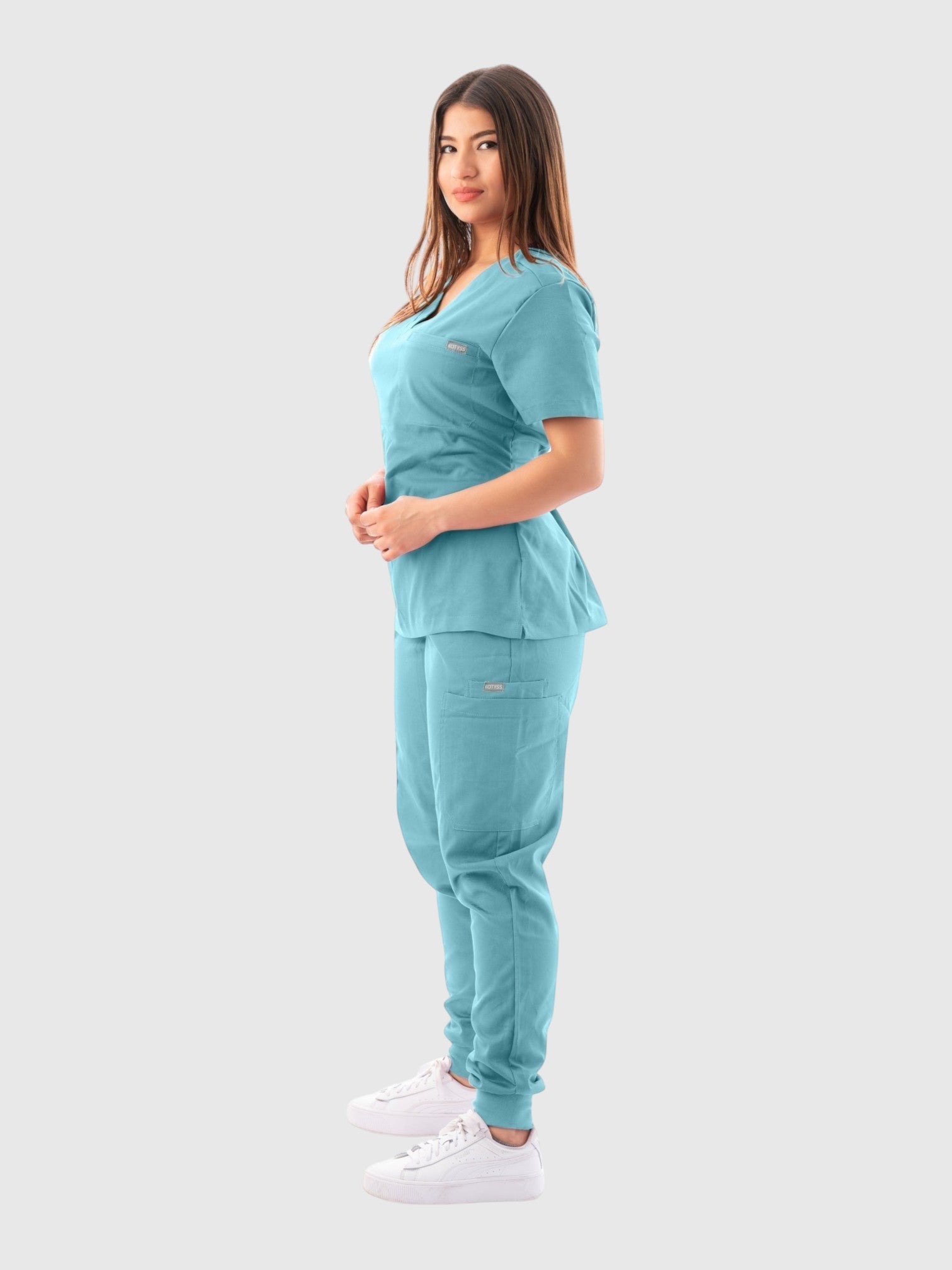 Model wearing a Kotyss light blue V-neck scrub top and matching jogger pants with multiple pockets