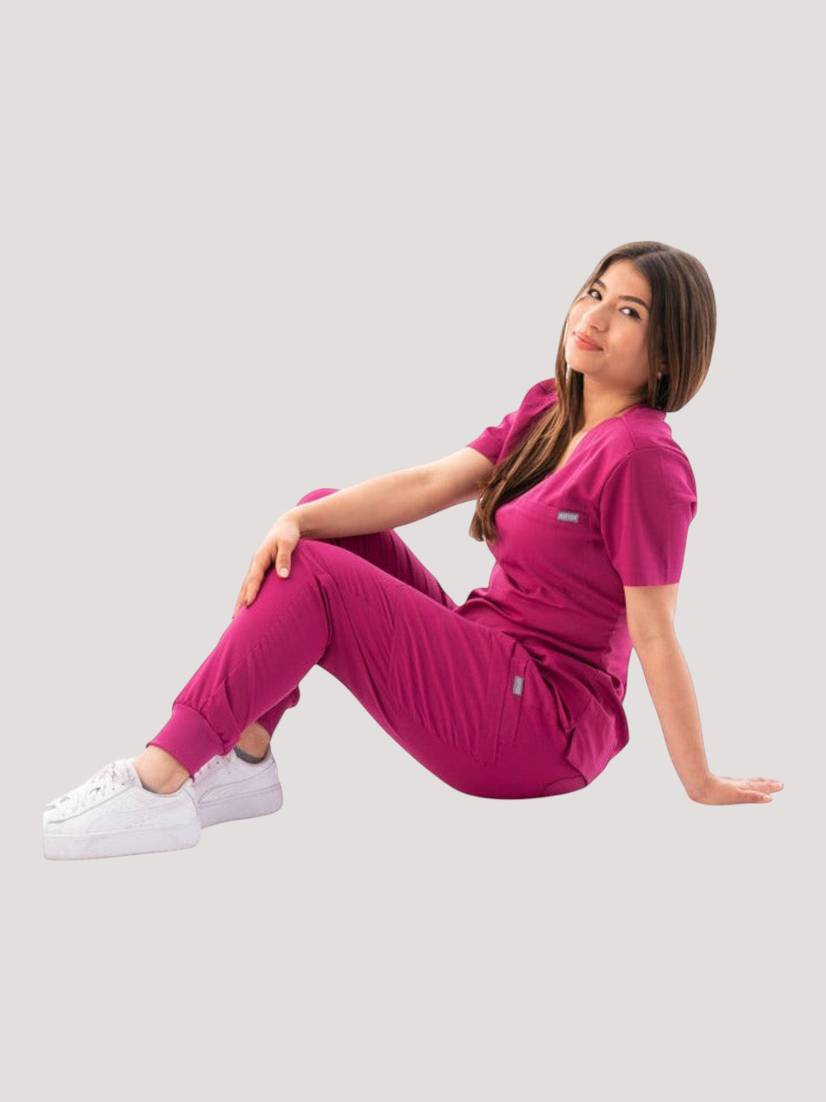 Kotyss women's magenta V-neck scrub top and jogger pants set with 4-way stretch fabric worn by a seated model.