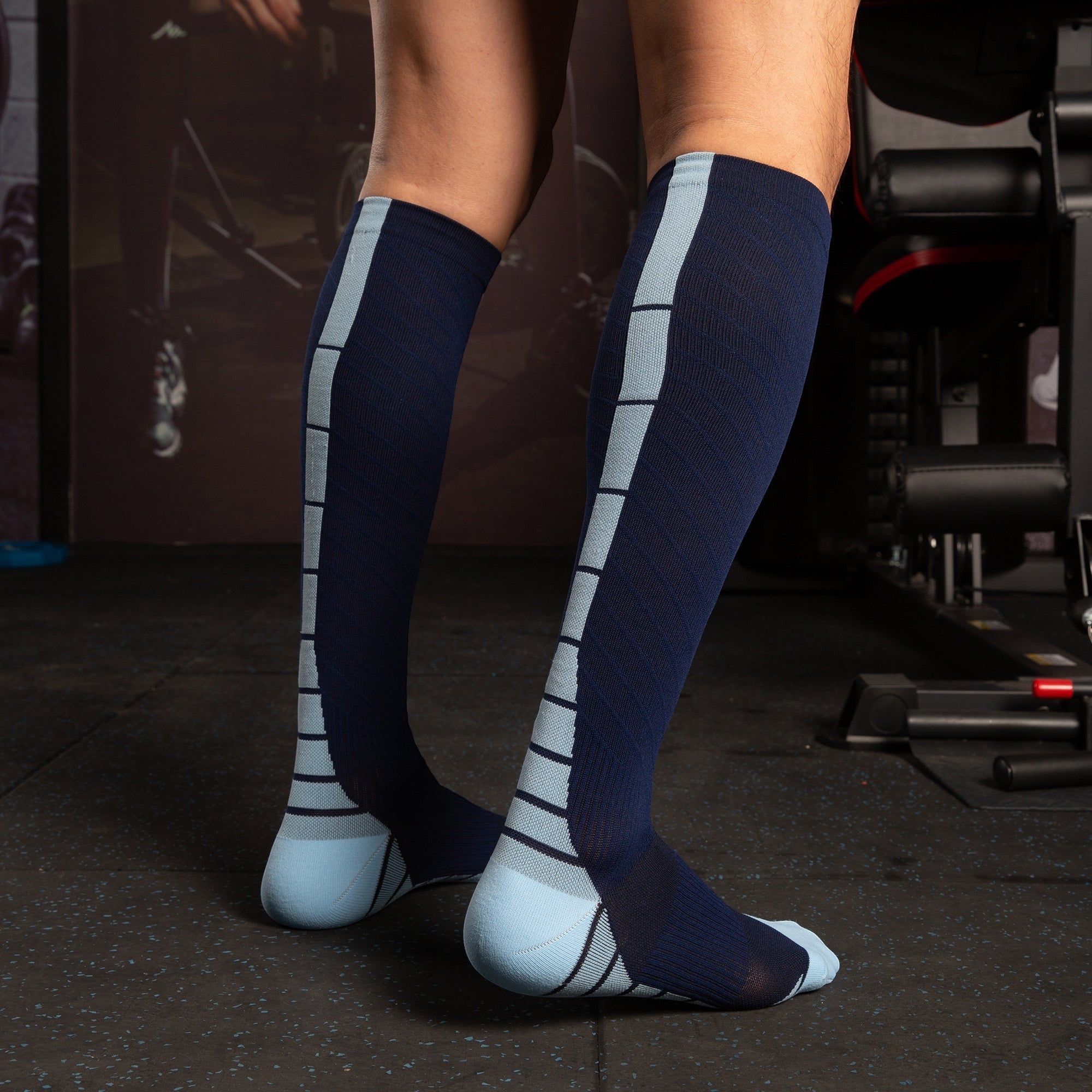 Kotyss navy blue and light blue knee-high athletic compression socks with seamless design on a person in a gym