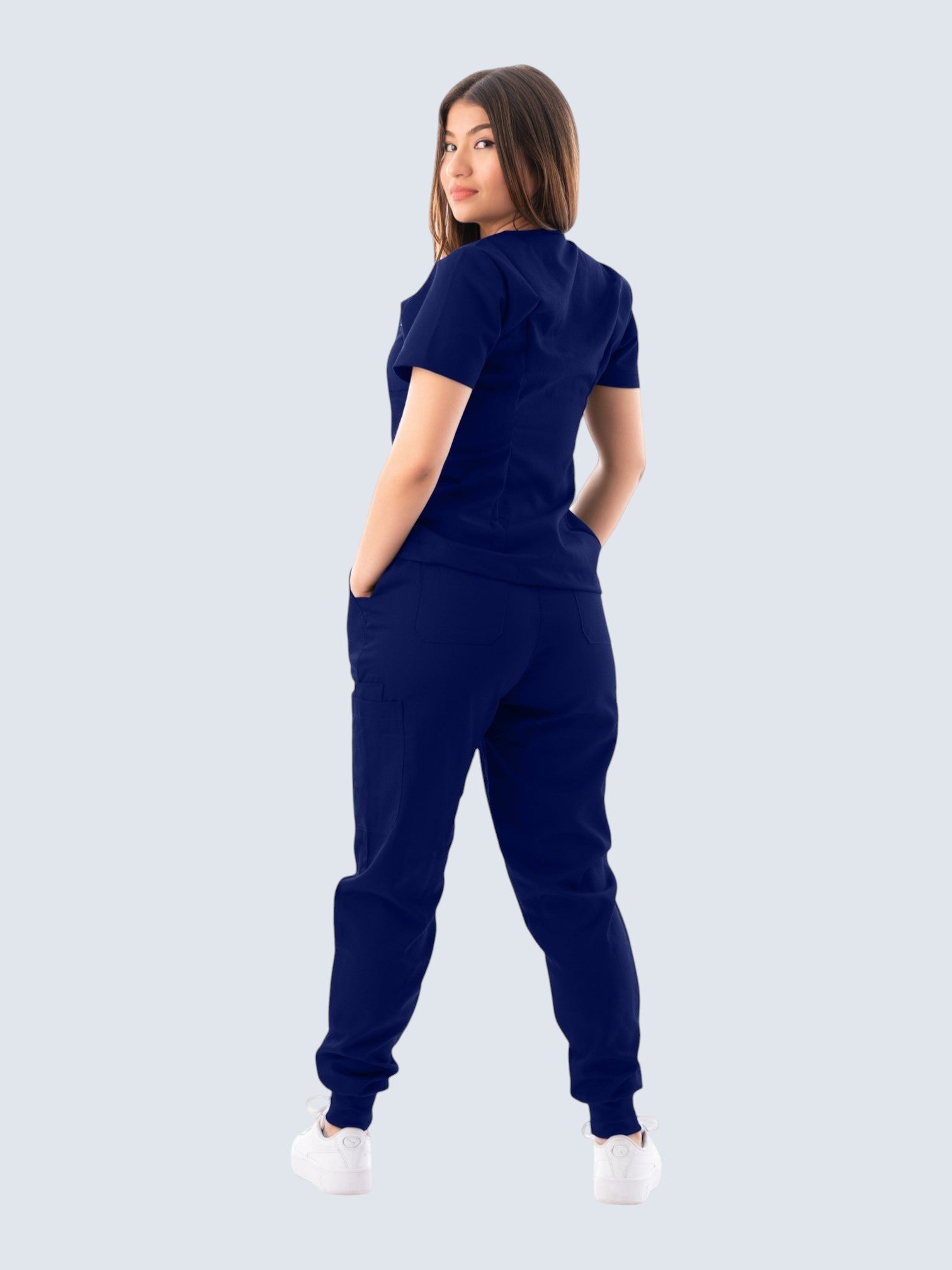 Kotyss navy blue V-neck scrub top and jogger pants set worn by a woman, showing back view with multiple pockets.