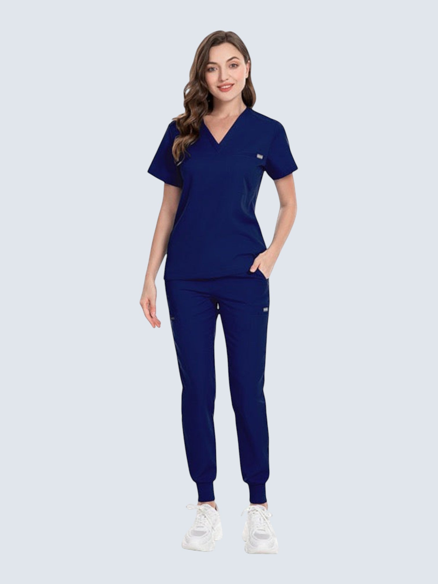 A woman wearing a navy blue Kotyss V-neck scrub top and matching jogger pants with multiple pockets.
