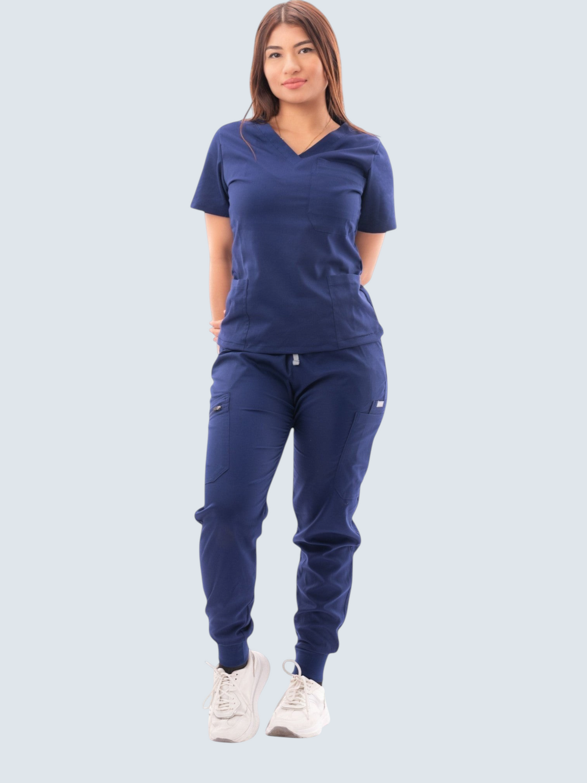 Woman wearing a navy blue Kotyss V-neck scrub top and multi-pocket jogger pants set with white sneakers