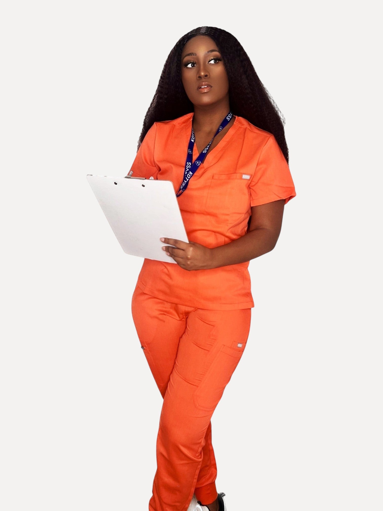 A woman wearing a vibrant orange Kotyss V-neck scrub top and matching jogger pants while holding a clipboard.