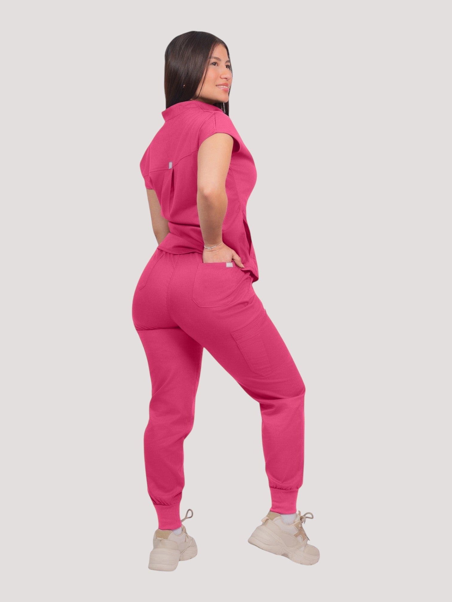 Kotyss women's hot pink collared scrub top and jogger set with multiple pockets, worn by a model on white background