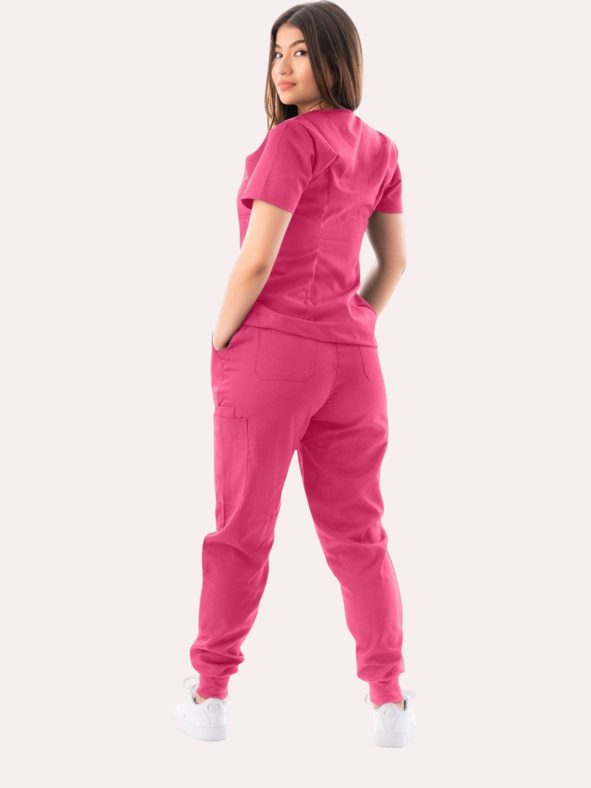 Kotyss women's pink V-neck scrub top and jogger pants set with multiple pockets, worn by a model from behind.