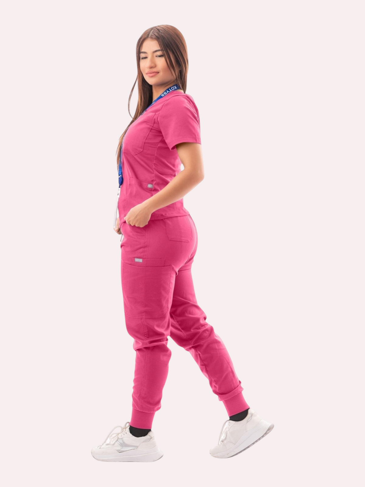 Kotyss women's pink V-neck scrub top and jogger pants set with multiple pockets worn by a model in profile view