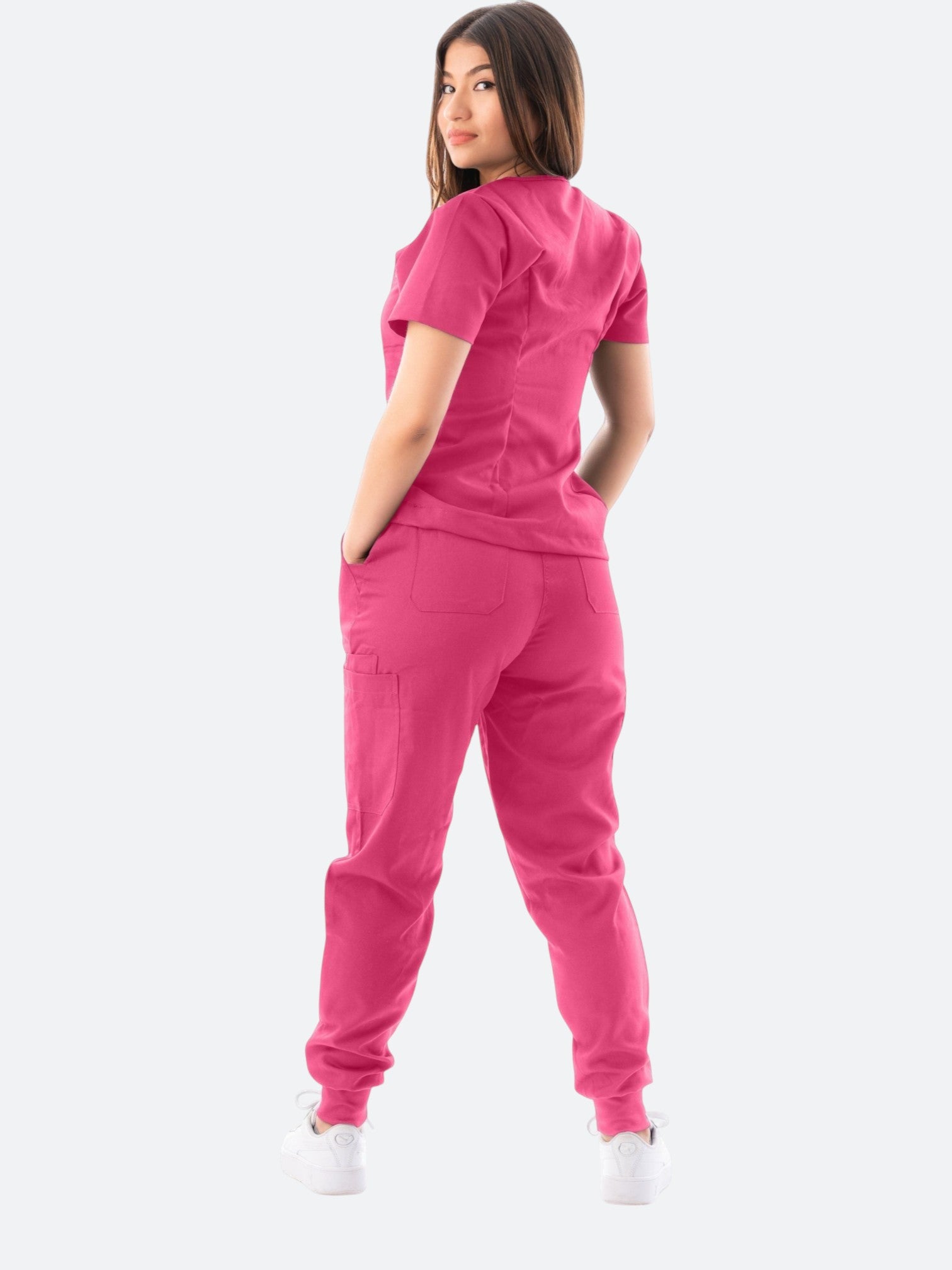 Kotyss women's pink V-neck scrub top and jogger pants set with multiple pockets, worn by a model from behind.