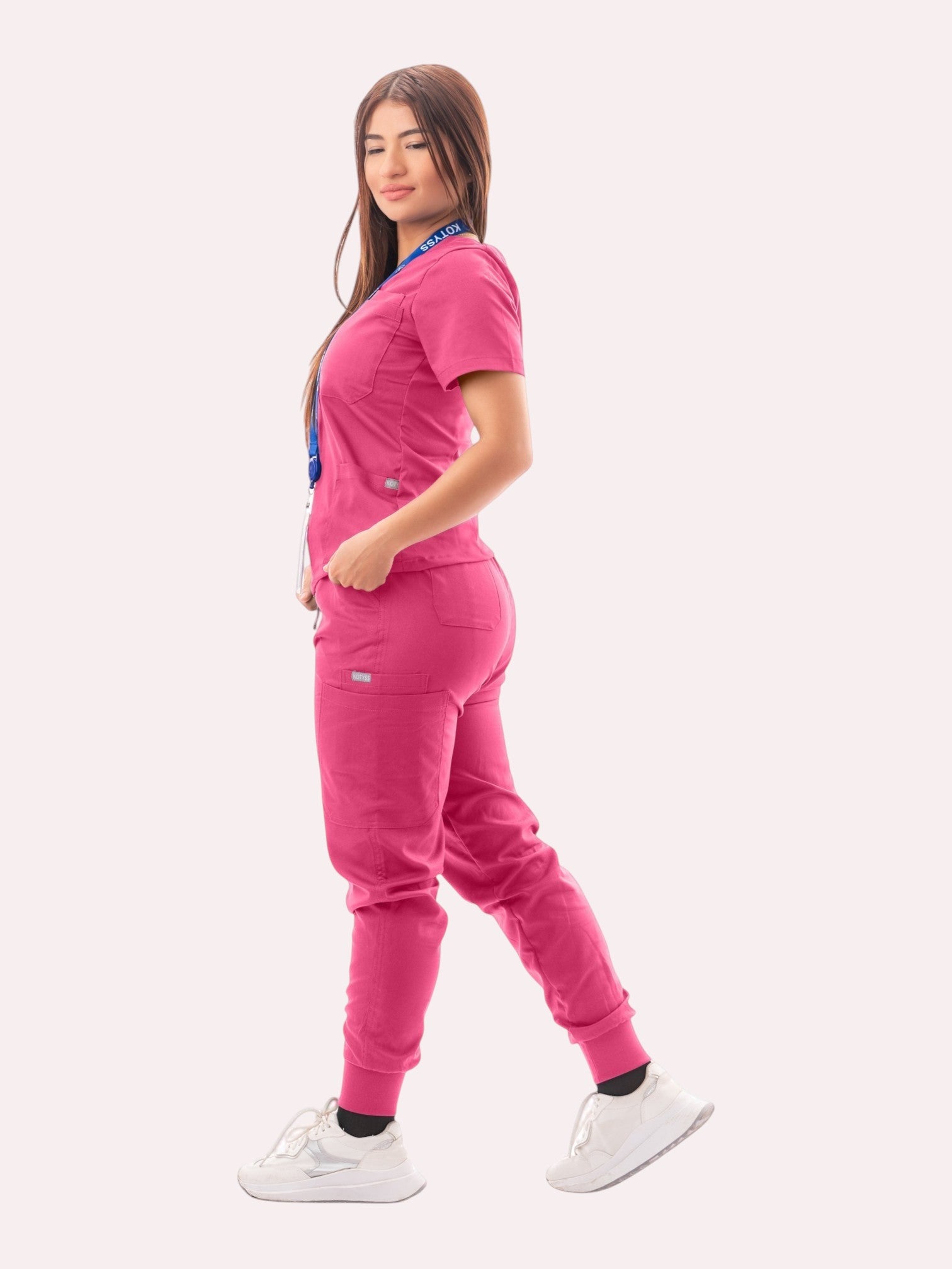 Kotyss women's pink V-neck scrub top and jogger pants set with multiple pockets worn by a model in profile view