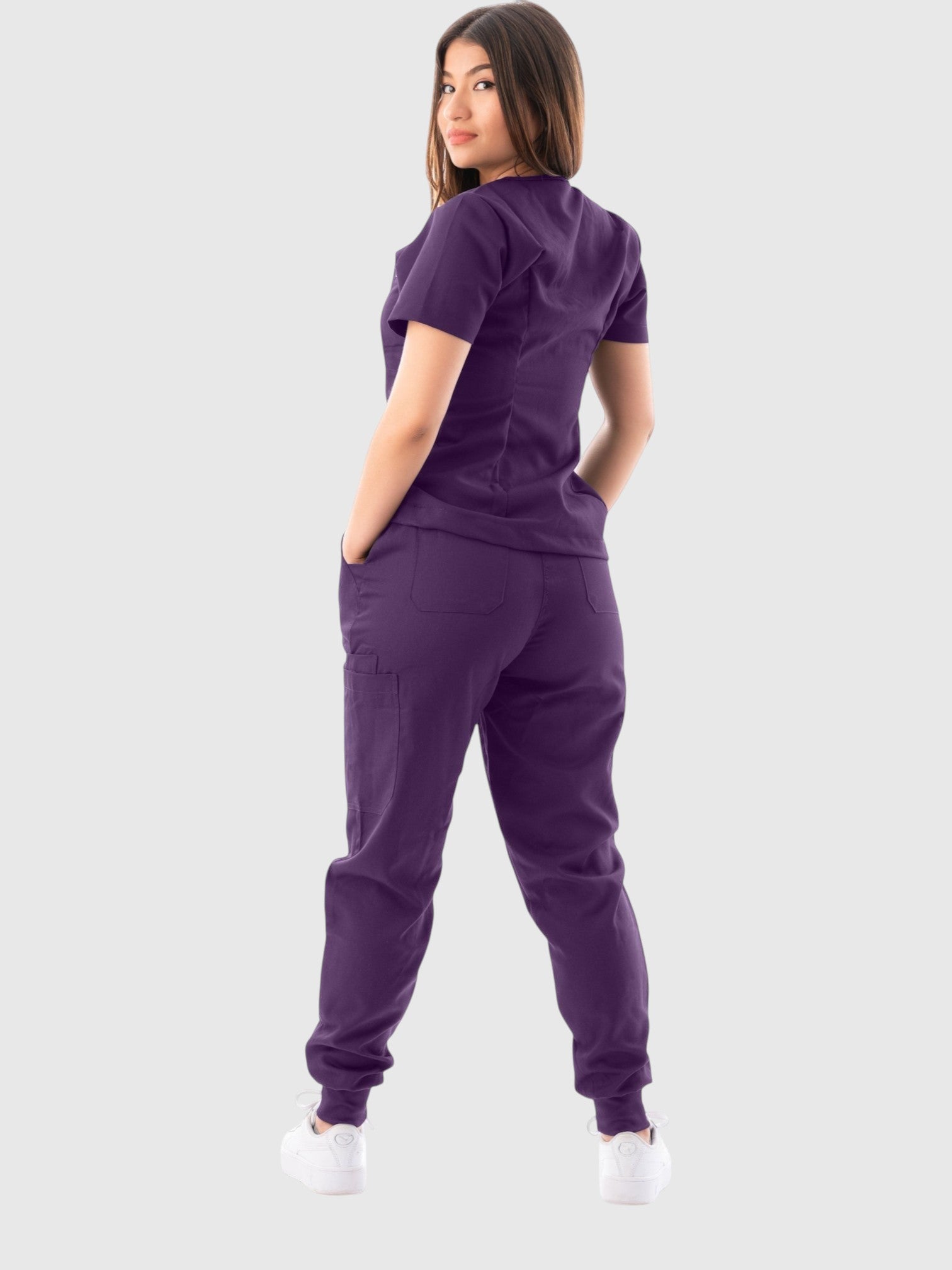 Kotyss purple V-neck scrub top and jogger pants set on a woman, showing back view with multiple utility pockets.