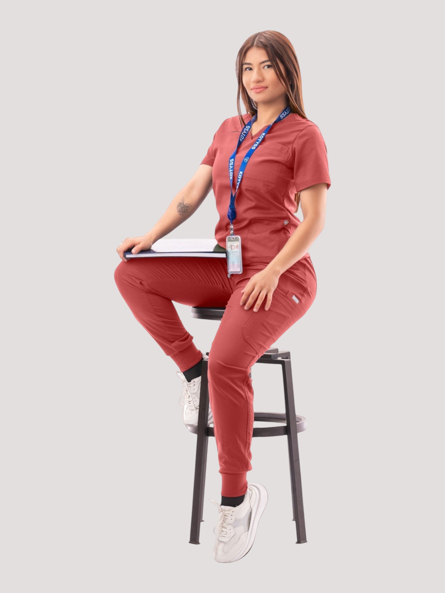 Kotyss women's rust-colored V-neck scrub top and jogger pants set with multiple pockets worn by a female model.
