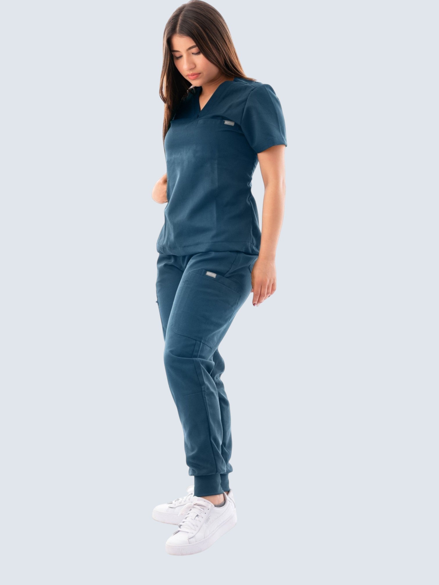 Kotyss women's dark blue V-neck scrub top and jogger pants set with multiple pockets, worn by a model.