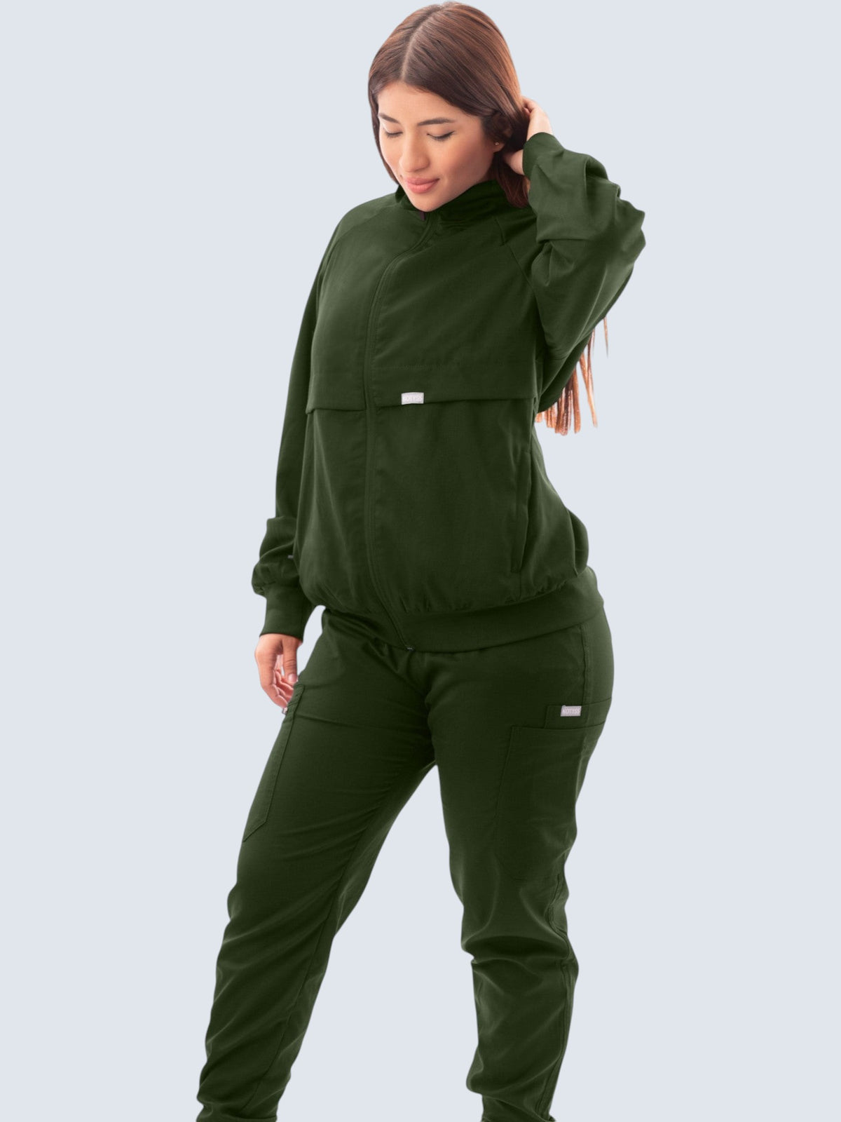 Kotyss women's dark green scrub jacket with a high windbreaker neck, ribbed cuffs, and functional pockets.